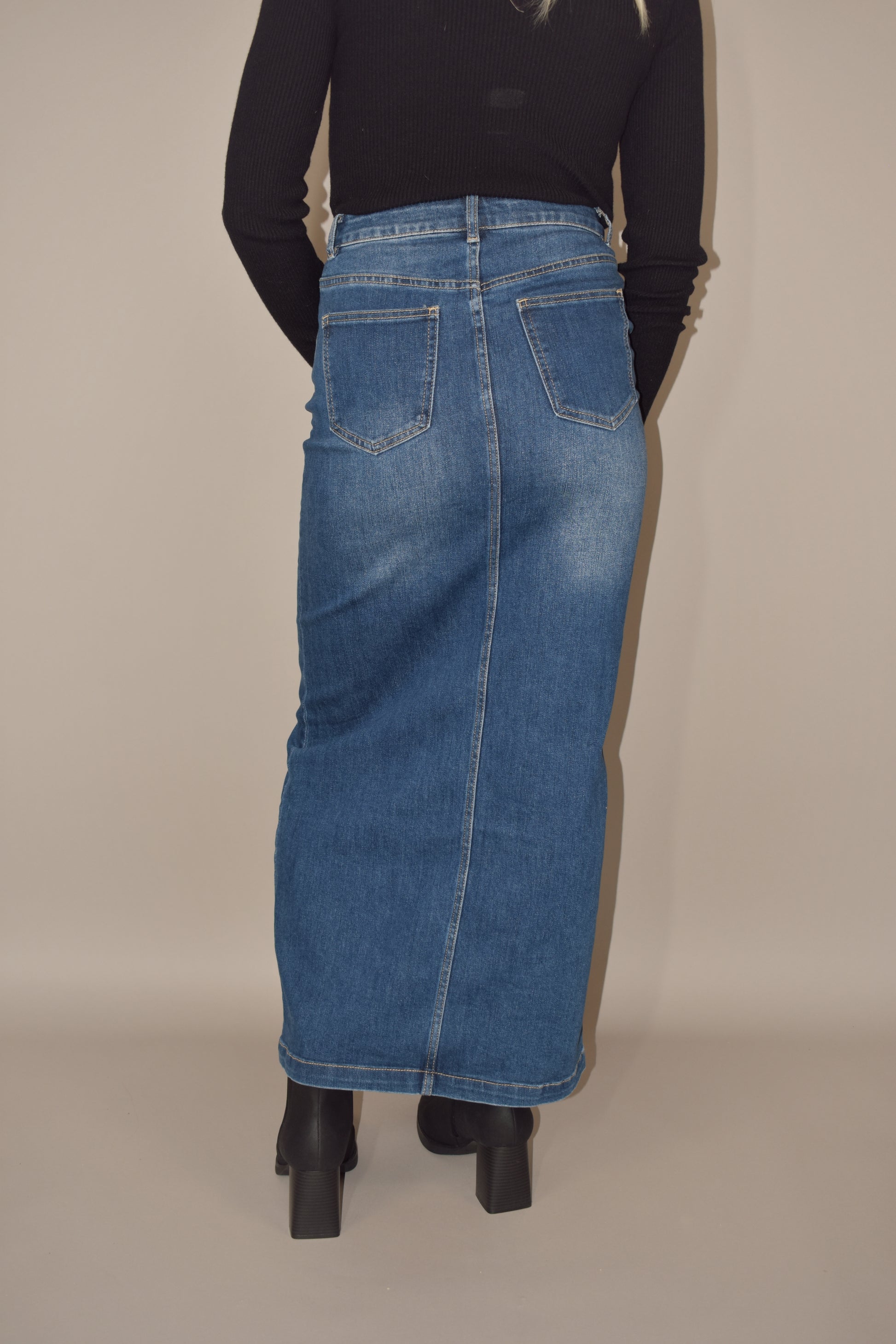 denim midi skirt that is more full length than midi and has a front slit with front and back pockets and is high waisted. made of stretch denim and is a medium dark wash.