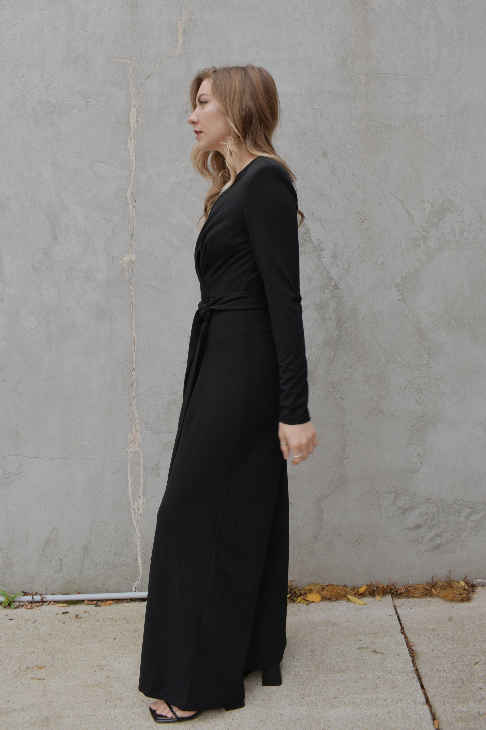 black wide leg long sleeve jumpsuit with wrap effect and fabric tie. pleated v neck with fitted arms and zip back enclosure