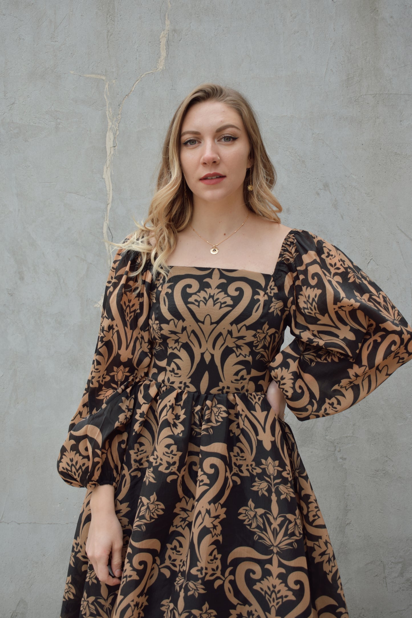 black and dark taupe dark bohemian print midi dress with square neckline front and back, balloon sleeves, flowy skirt, and zip back enclosure