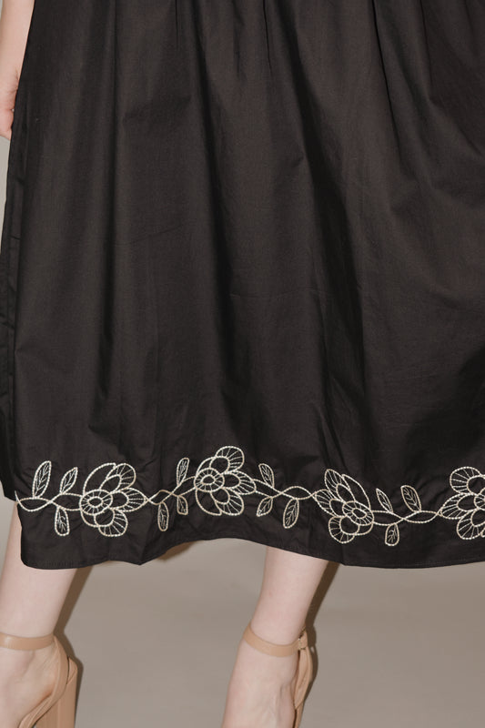 black midi dress with cream embroidered flower vine along hem, smocked bodice, square neckline, flutter shoulder detail, flowy yet tailored feel