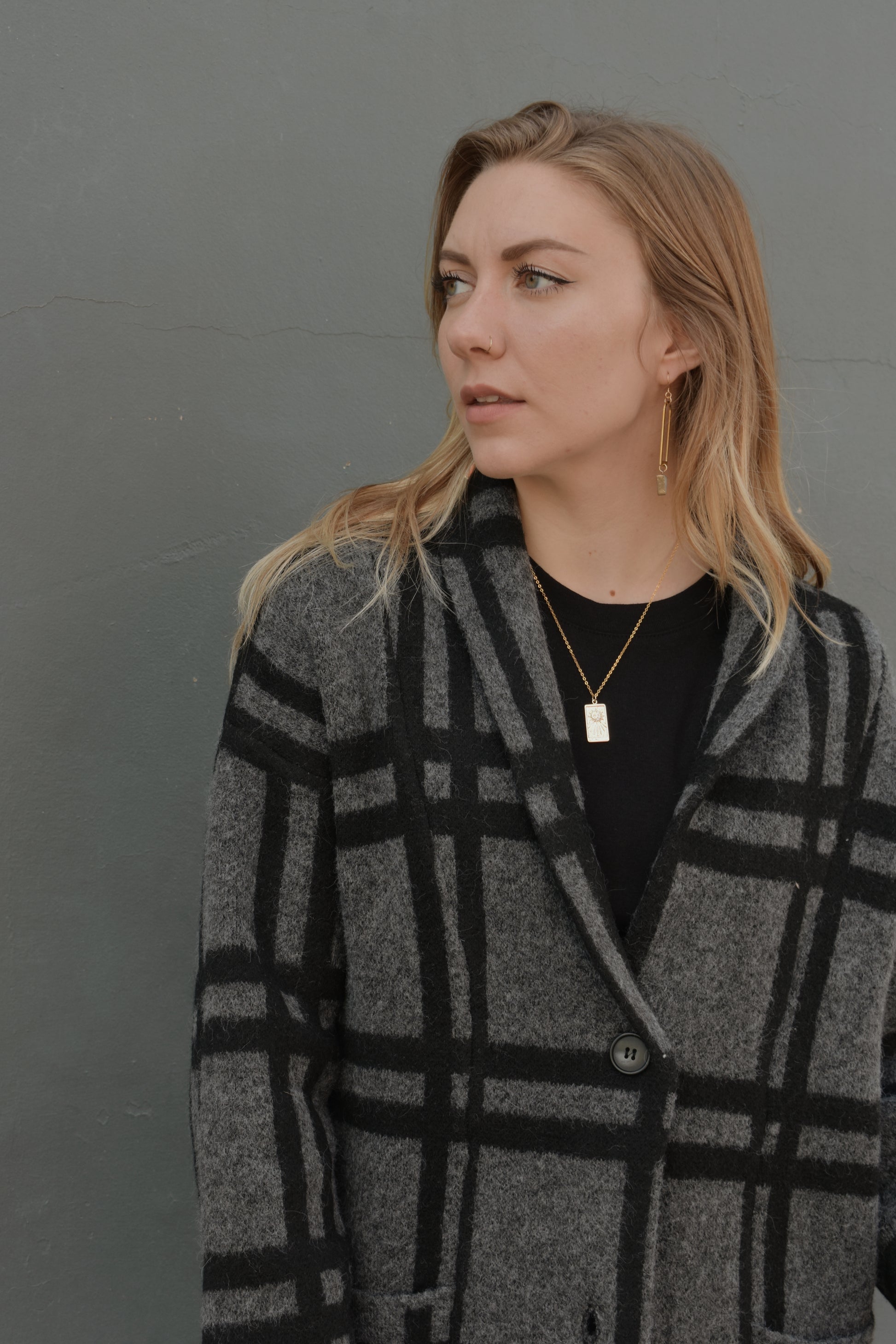 black and grey wide pattered plaid jacket that feels like a cardigan and coat mix, front patch pockets, 3 front buttons for enclosure, folded collar, slightly oversized, drop shoulder, hits at mid calf.