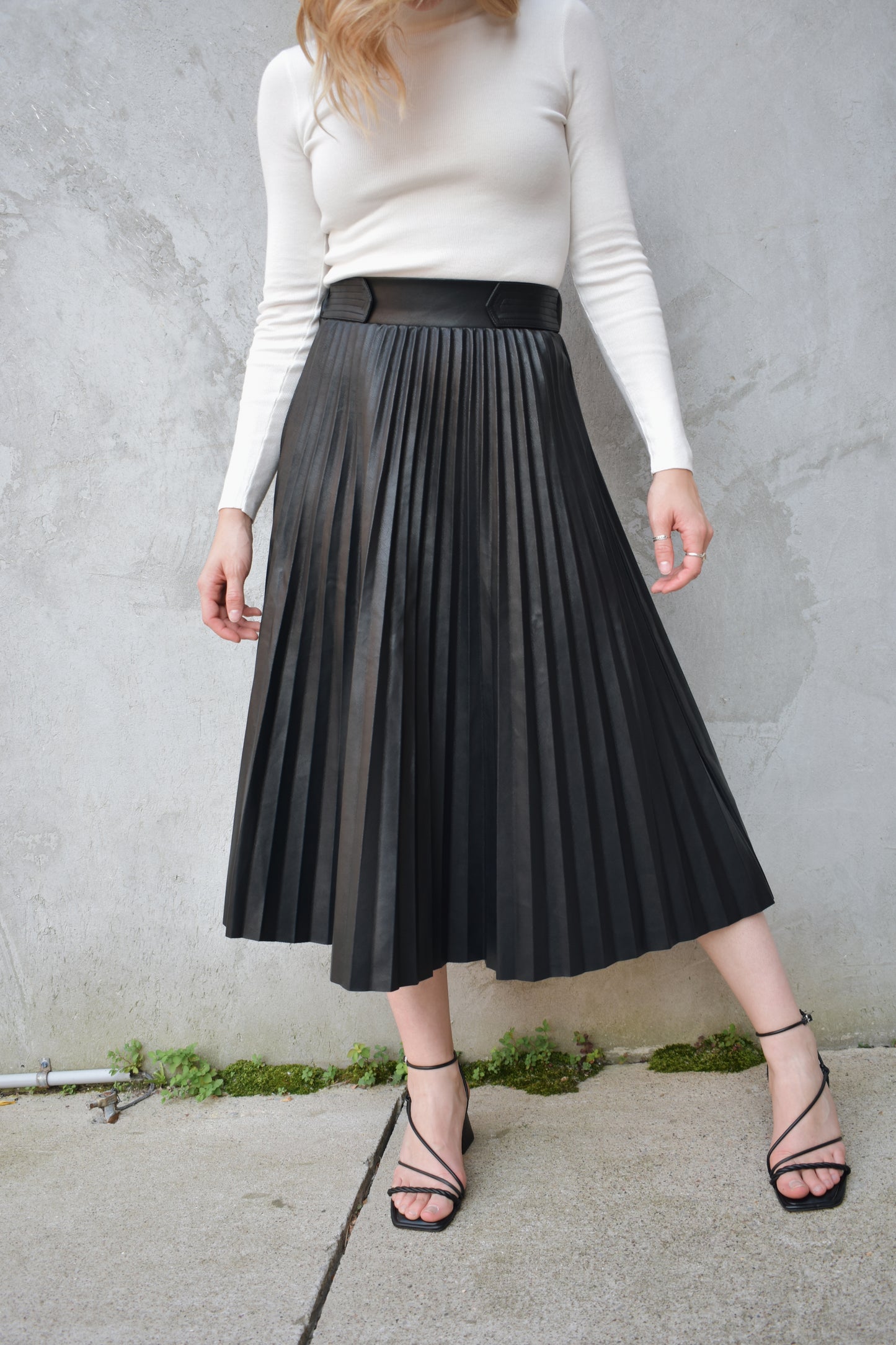 high waisted fully pleated faux leather skirt midi length waist band has tab detailing back of waistband has elastic in band for stretch and it has an invisible zip enclosure on the side