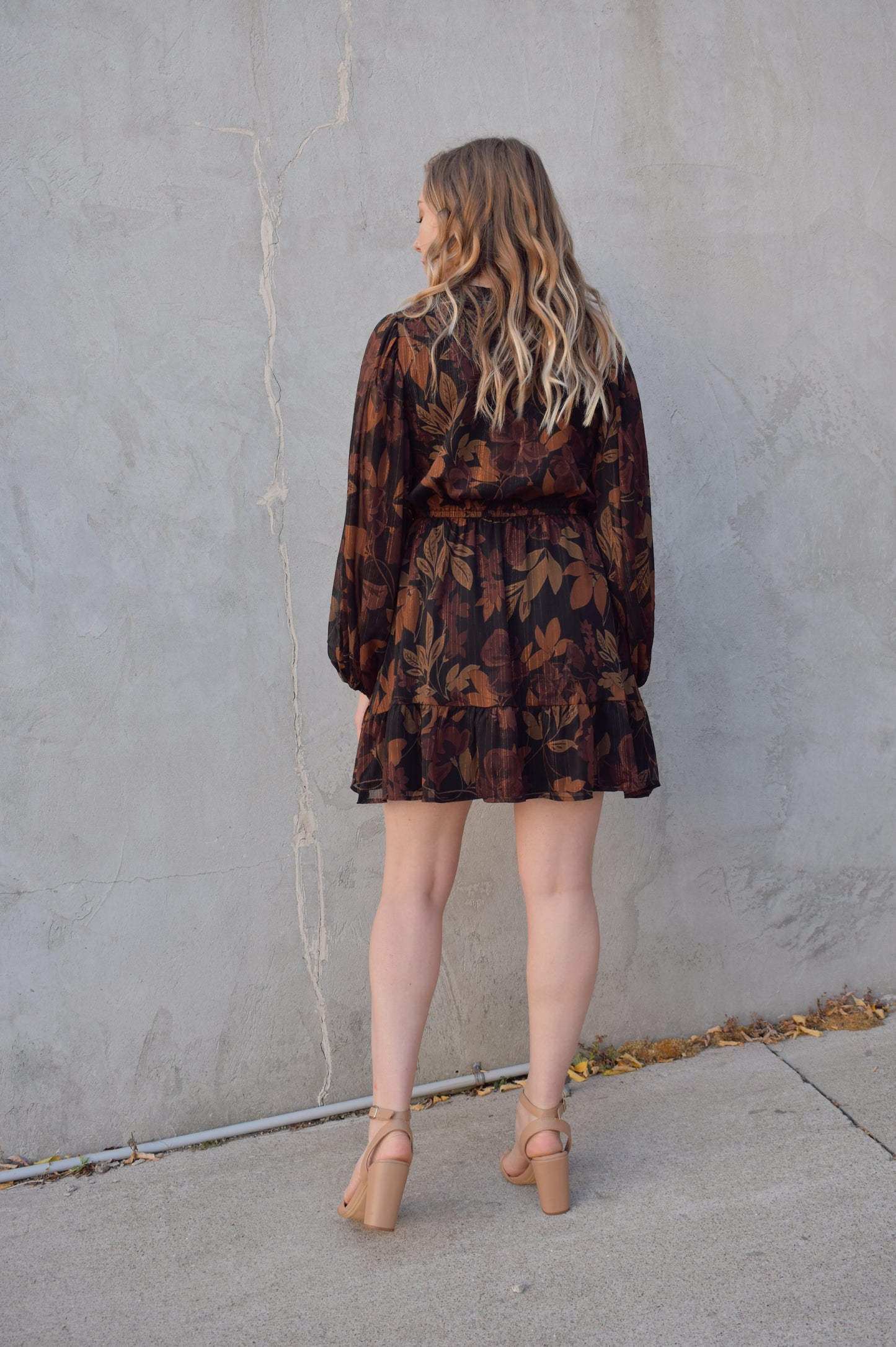 long sleeve chiffon mini dress with leaf print. black background with shades of brown in print. gold tread throughout. sheer balloon sleeves. split v neckline with tie, elastic waist, tiered just above hem making it swing and flowy. lined.