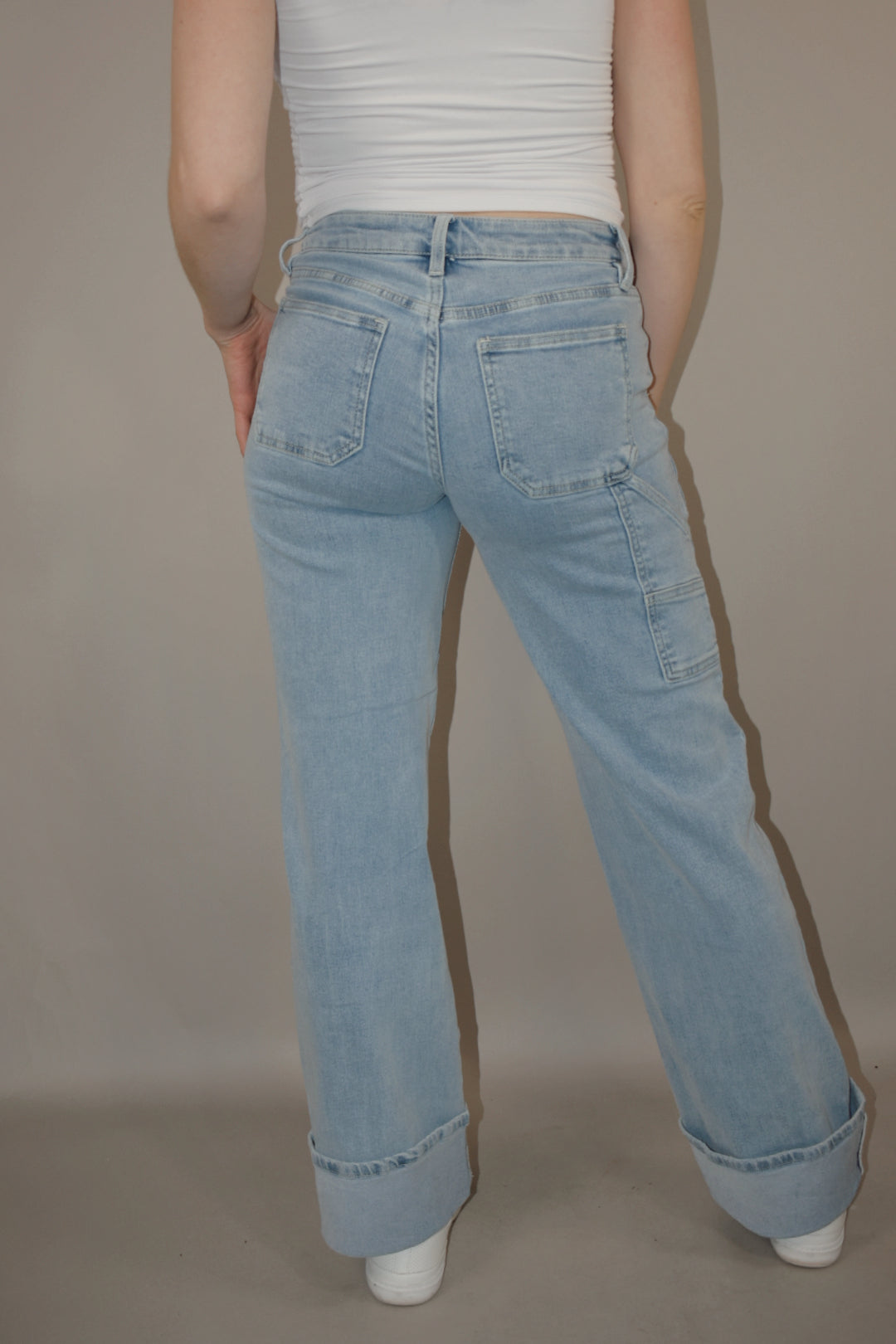 wide leg cuffed light wash stretch denim jeans with deep front patch style pockets and has a side carpenter pocket, no holes, zip and button enclosure, high rise.