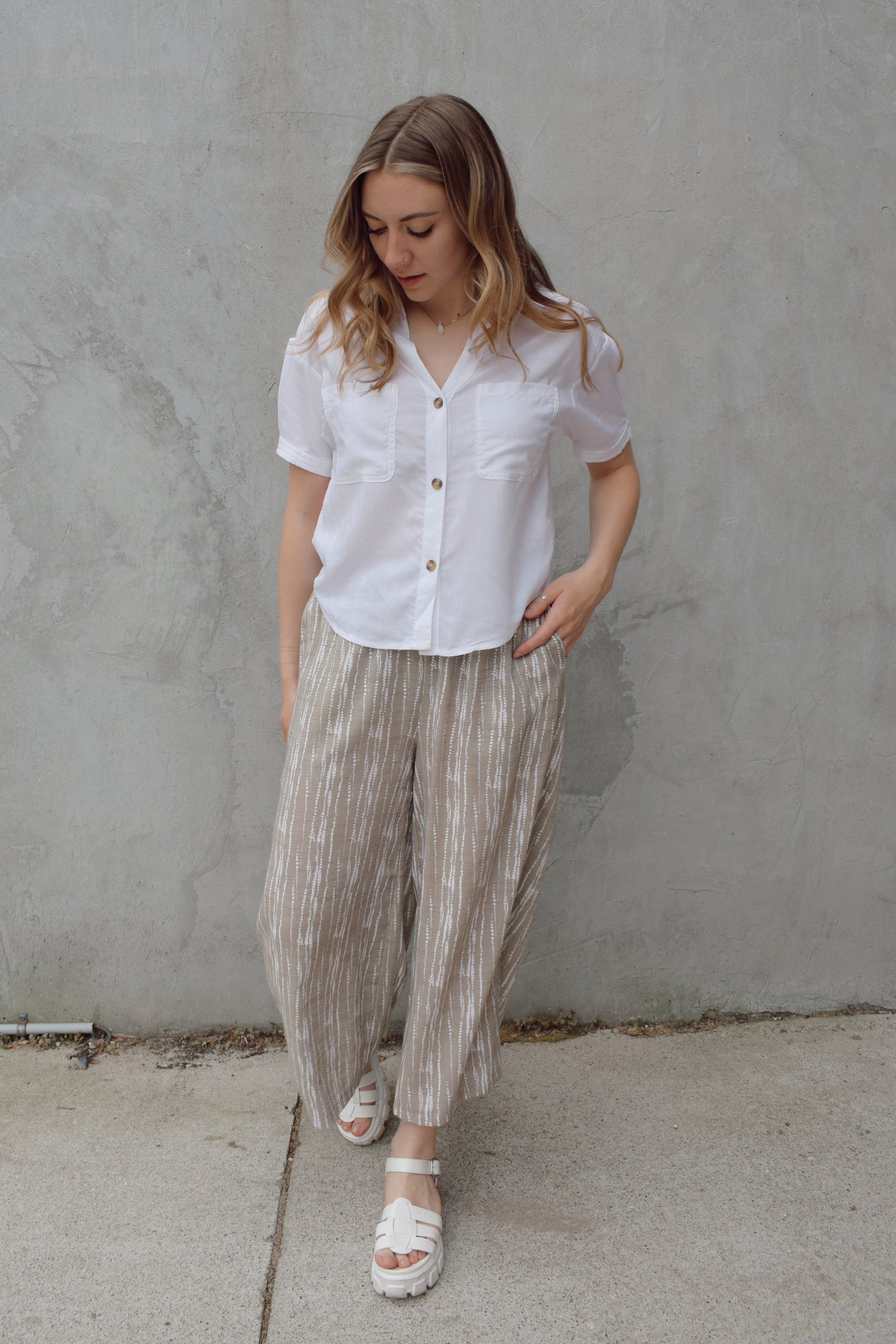 white linen button down, short sleeve, v neck with collar, 3 brown buttons, patch breast pockets, scoop hemline, button detail on back of sleeve cuff