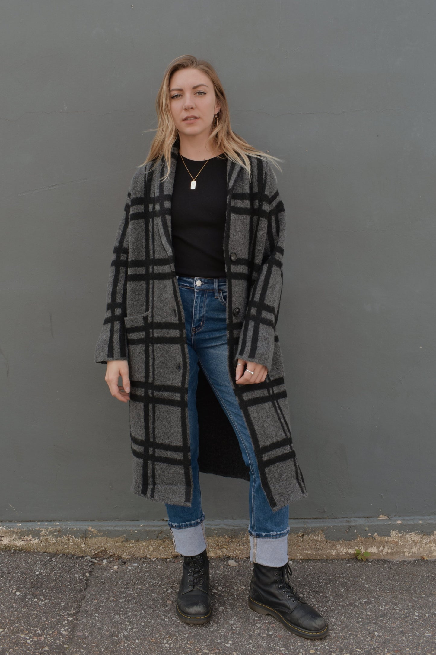 black and grey wide pattered plaid jacket that feels like a cardigan and coat mix, front patch pockets, 3 front buttons for enclosure, folded collar, slightly oversized, drop shoulder, hits at mid calf.