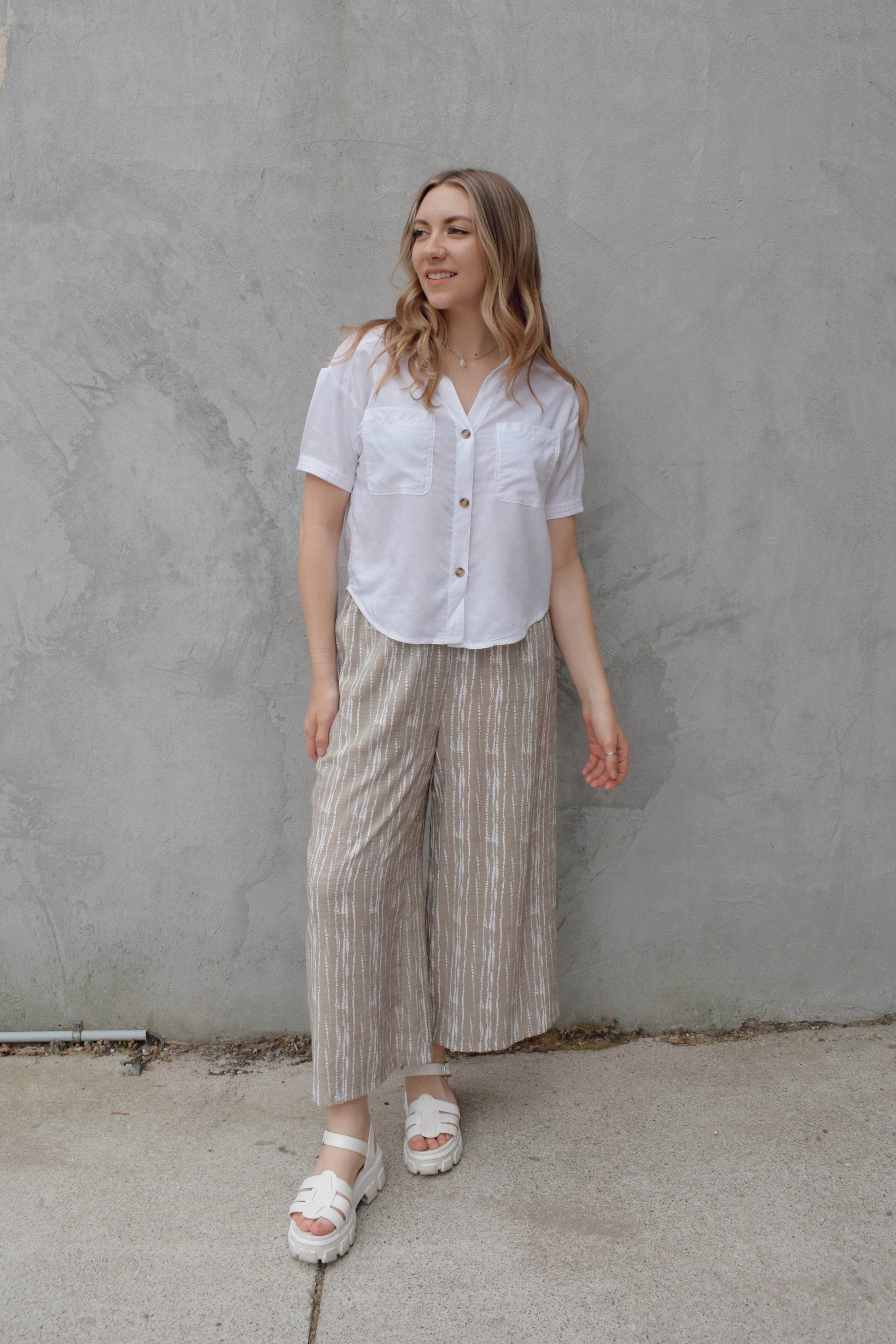 white linen button down, short sleeve, v neck with collar, 3 brown buttons, patch breast pockets, scoop hemline, button detail on back of sleeve cuff