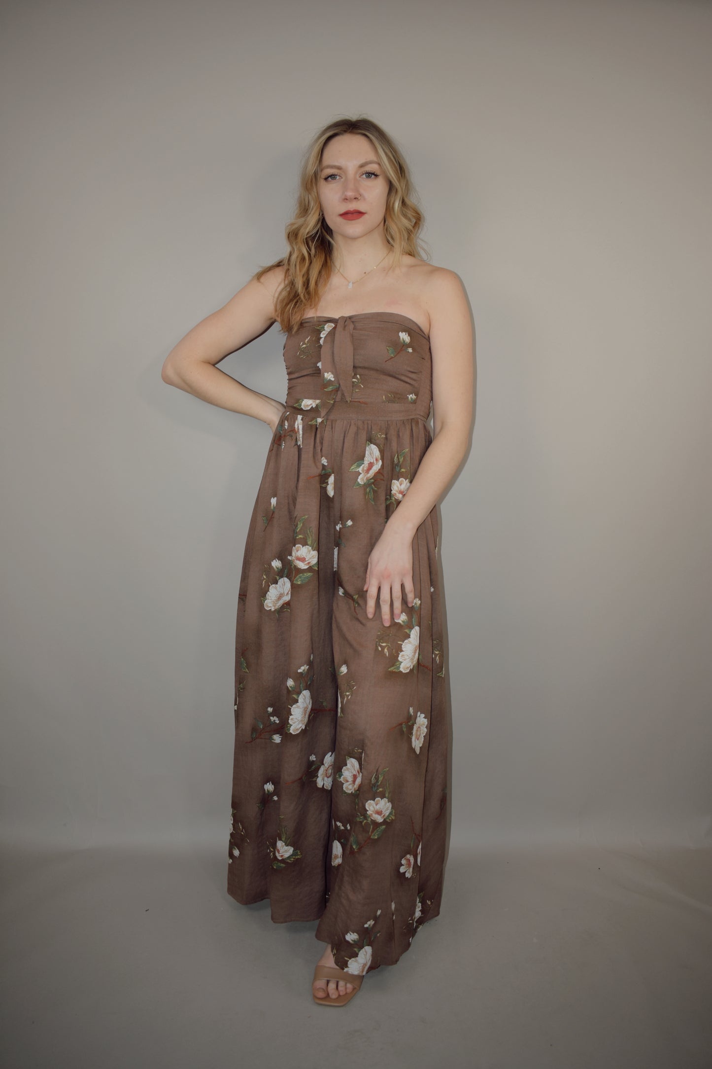 strapless wide leg flowy floral jumpsuit with tie and eyelet hole on front of bodice, has a elastic back panel on bodice full length, no pockets, is lined