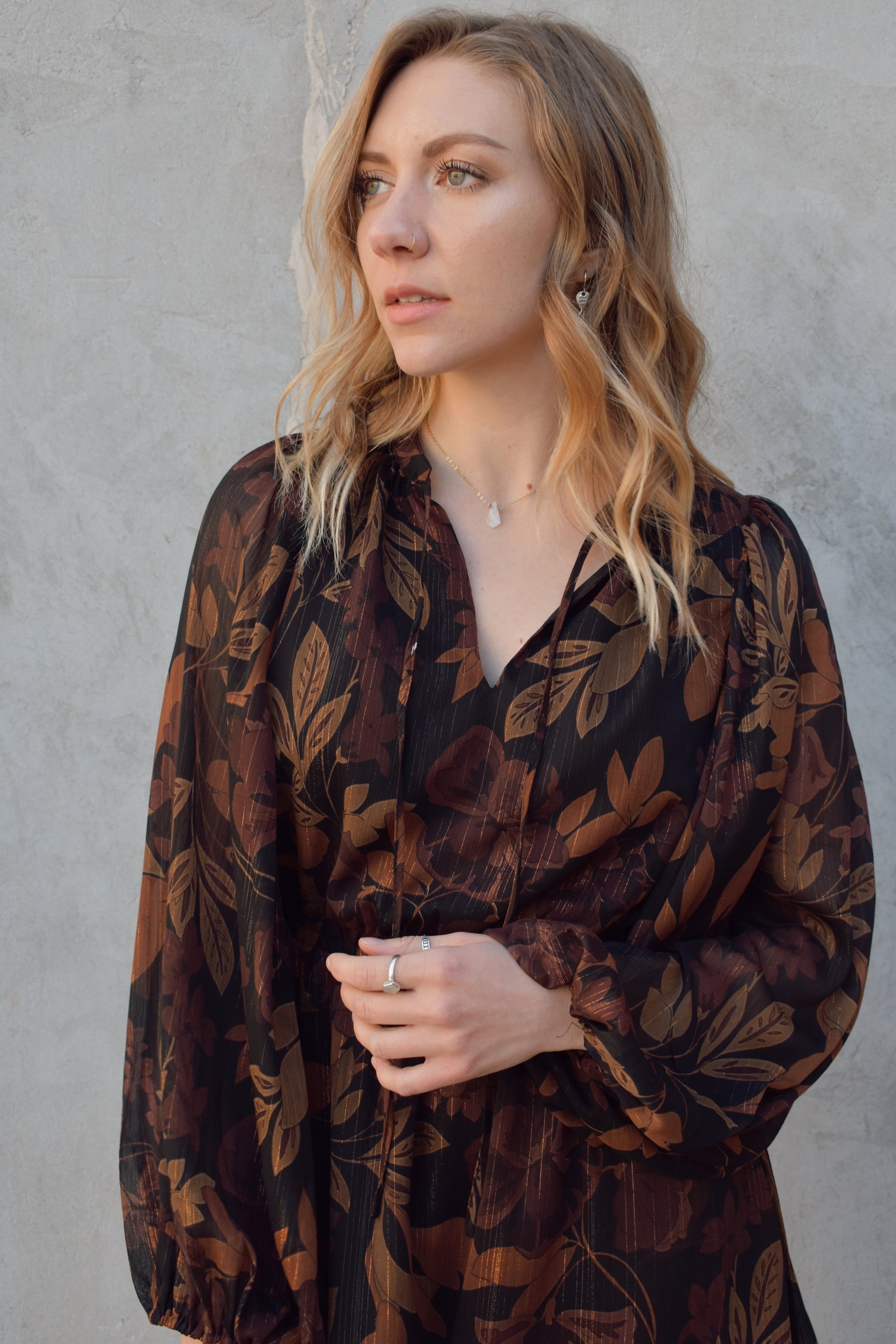 long sleeve chiffon mini dress with leaf print. black background with shades of brown in print. gold tread throughout. sheer balloon sleeves. split v neckline with tie, elastic waist, tiered just above hem making it swing and flowy. lined.