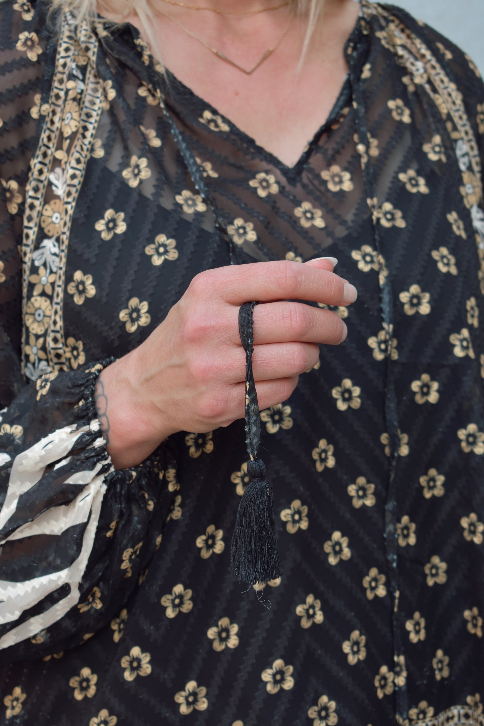 boho sheer long sleeve blouse. black background with gold and cream print. v neck with long tassels. built in black cami liner, not fitted. full length.