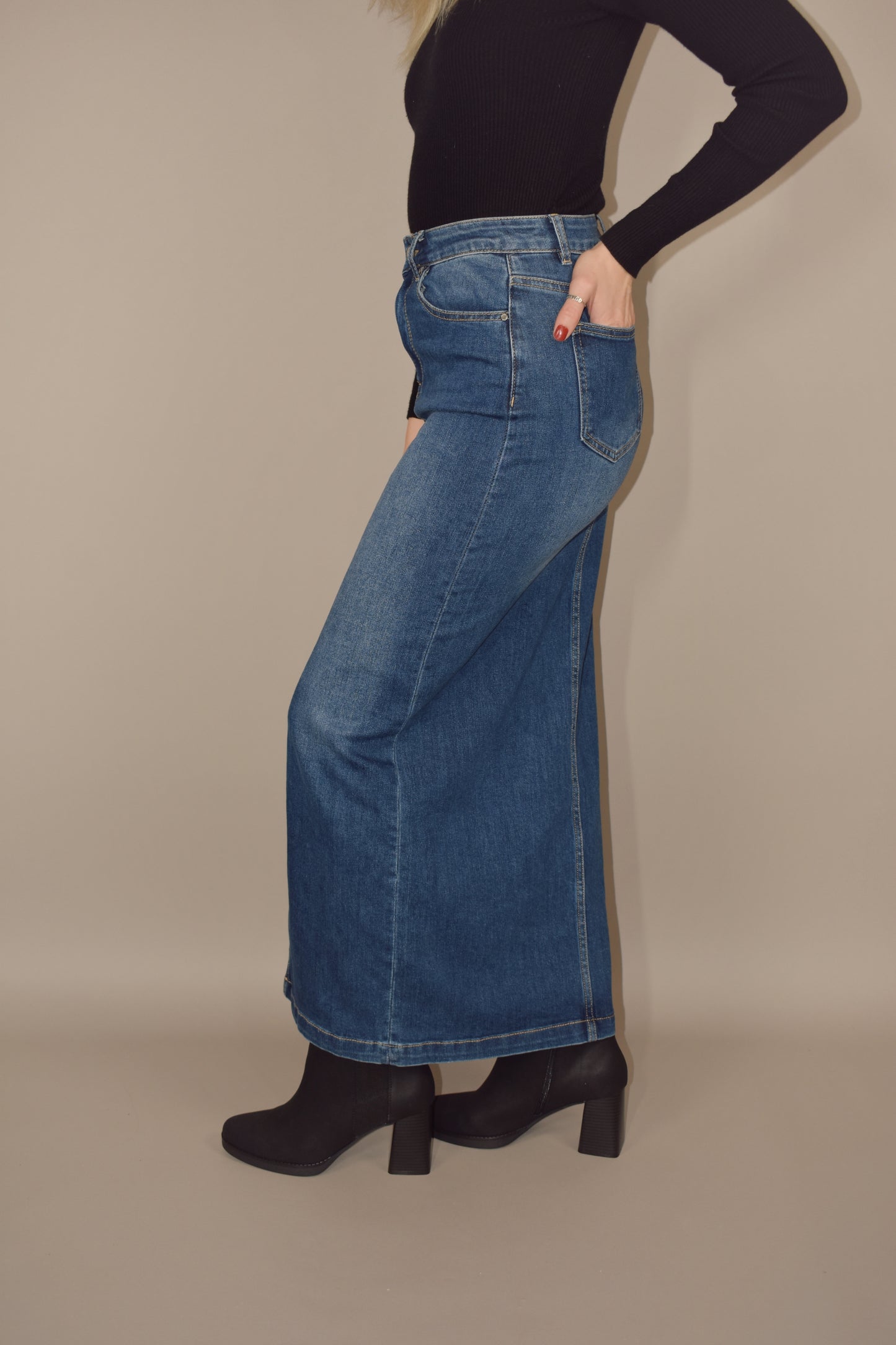 denim midi skirt that is more full length than midi and has a front slit with front and back pockets and is high waisted. made of stretch denim and is a medium dark wash.