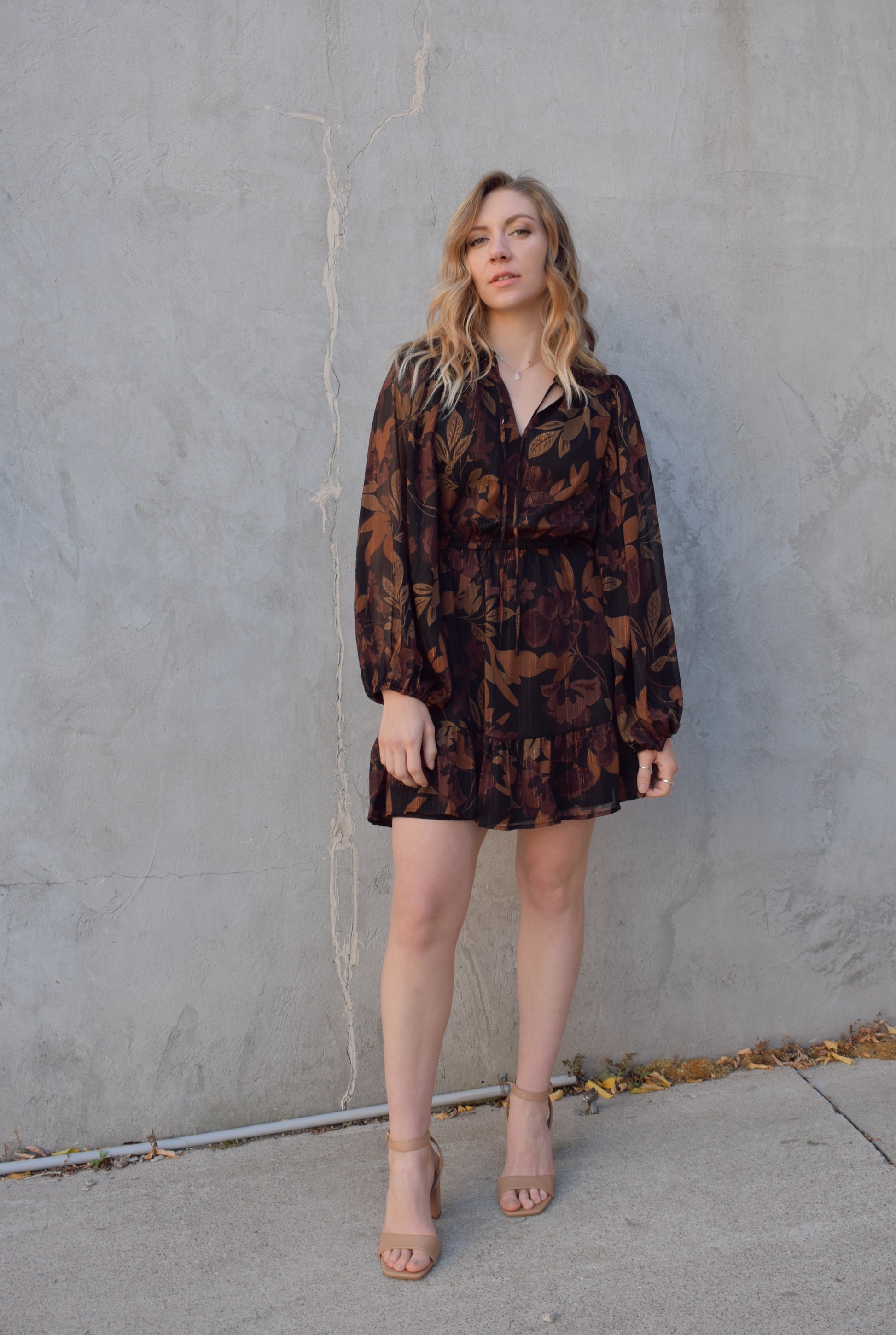 long sleeve chiffon mini dress with leaf print. black background with shades of brown in print. gold tread throughout. sheer balloon sleeves. split v neckline with tie, elastic waist, tiered just above hem making it swing and flowy. lined.