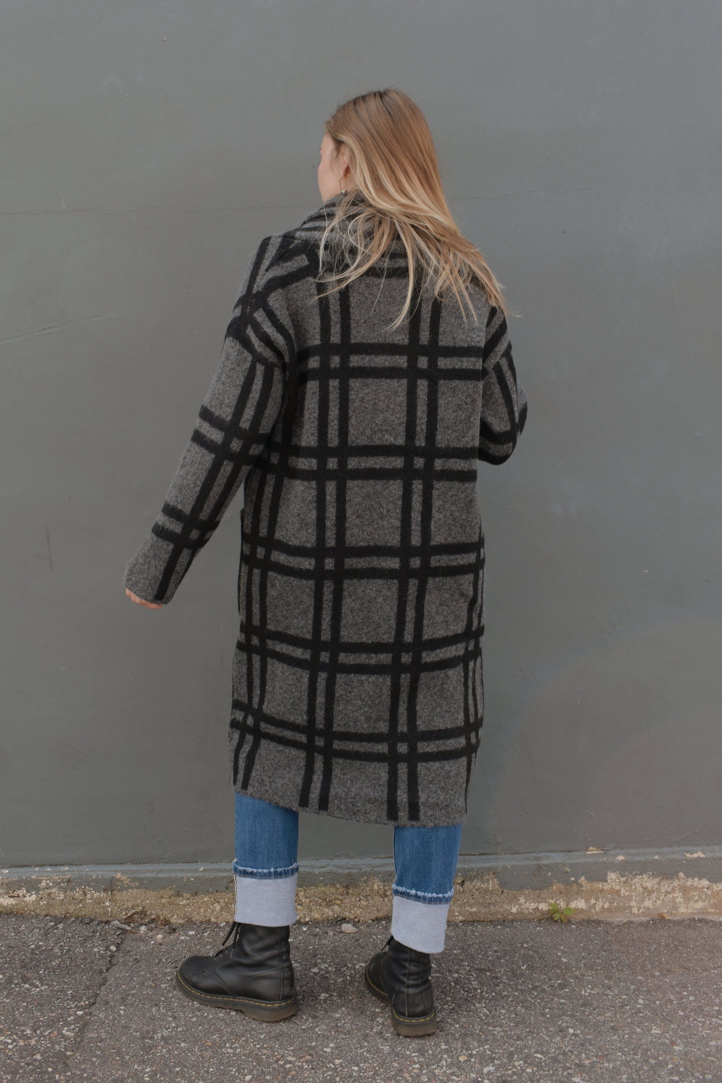 black and grey wide pattered plaid jacket that feels like a cardigan and coat mix, front patch pockets, 3 front buttons for enclosure, folded collar, slightly oversized, drop shoulder, hits at mid calf.