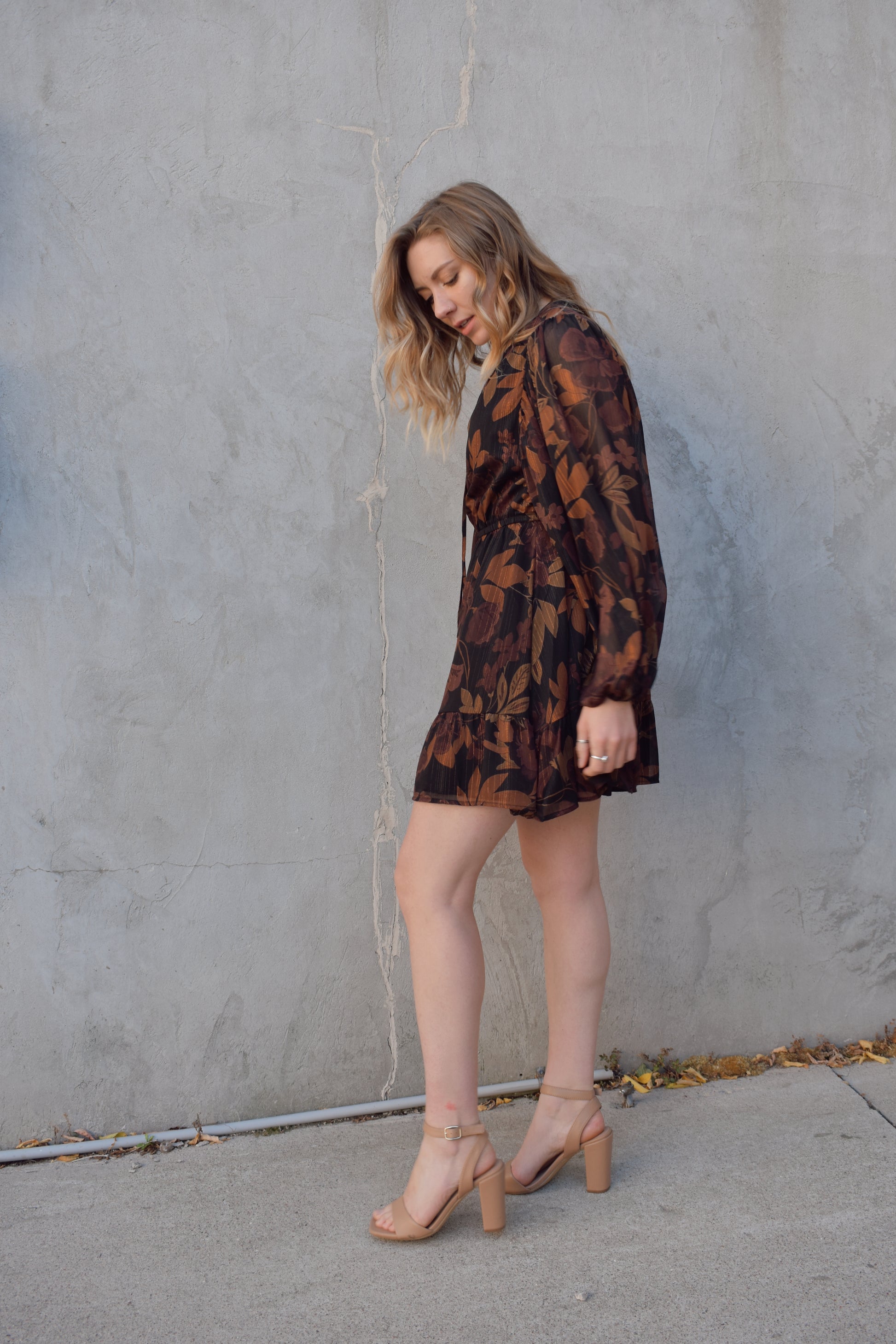 long sleeve chiffon mini dress with leaf print. black background with shades of brown in print. gold tread throughout. sheer balloon sleeves. split v neckline with tie, elastic waist, tiered just above hem making it swing and flowy. lined.