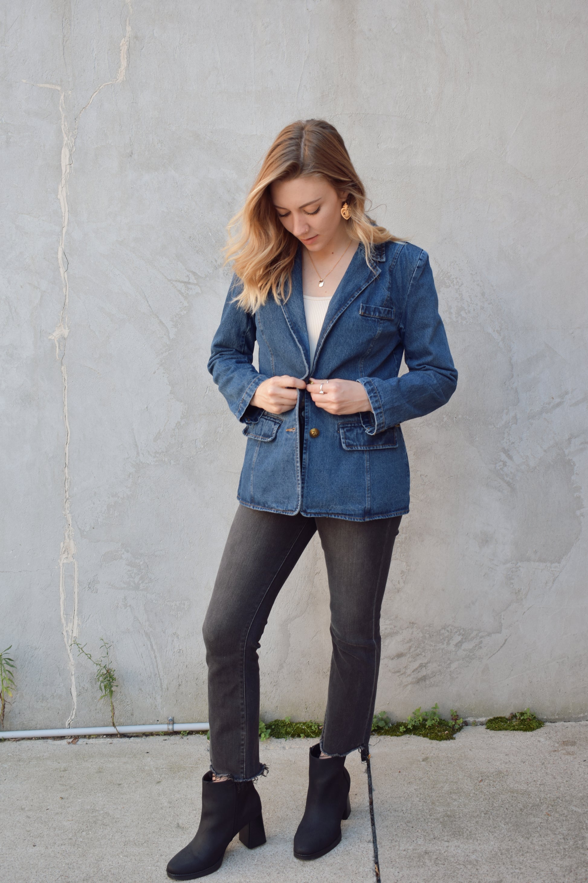 dark wash denim blazer with two gold buttons with an anchor design on them.  pockets with flaps on top, one breast pocket, fitted. full length. slit on back middle hem