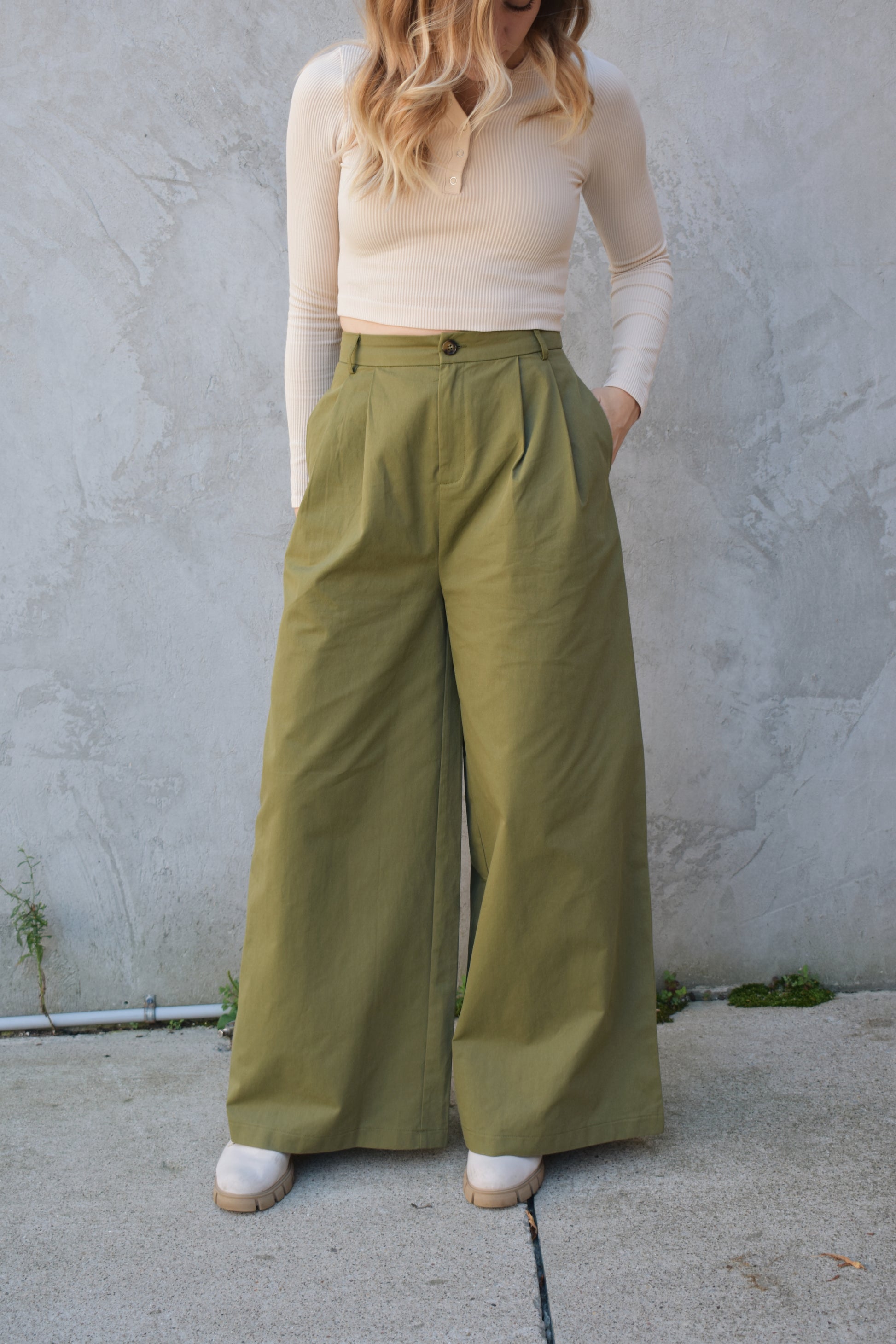 Super wide leg olive green twill trousers with pleats at the top. high waisted with zip and button enclosure. has beltloops and pockets. full length. good for tall ladies.