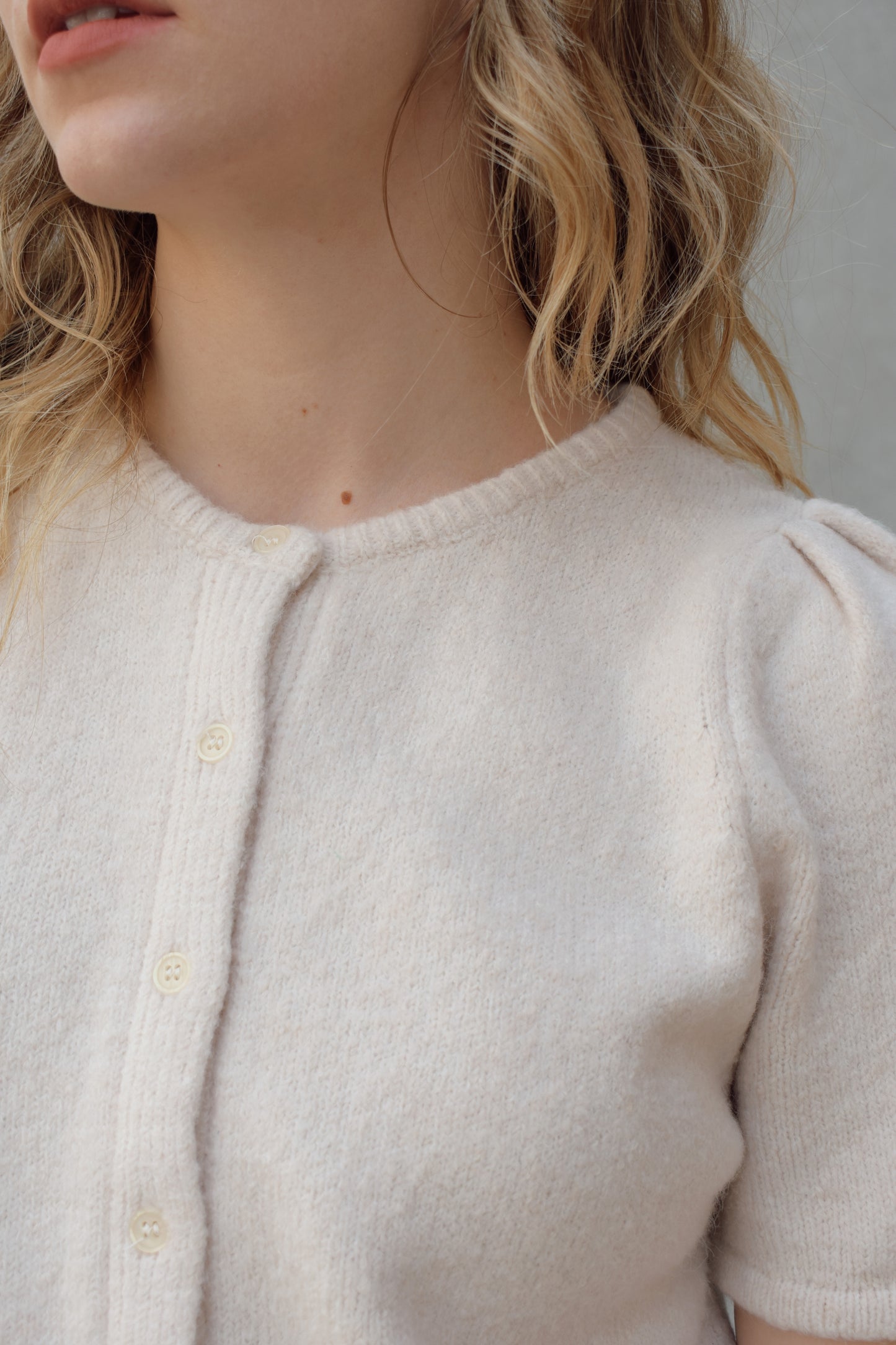 short sleeve cardigan sweater with crew neckline and slight puff sleeves gathered at shoulder, ribbed hem, straight fit, hits at waistline