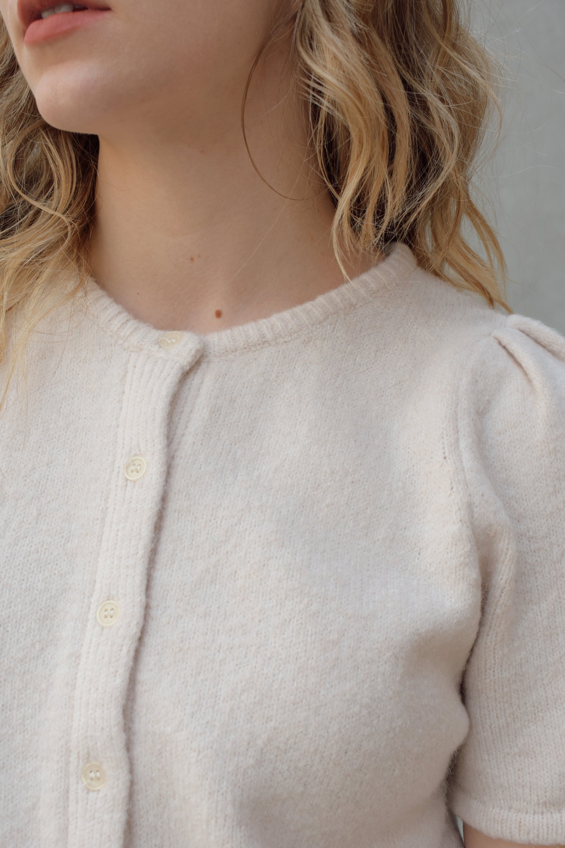 short sleeve cardigan sweater with crew neckline and slight puff sleeves gathered at shoulder, ribbed hem, straight fit, hits at waistline