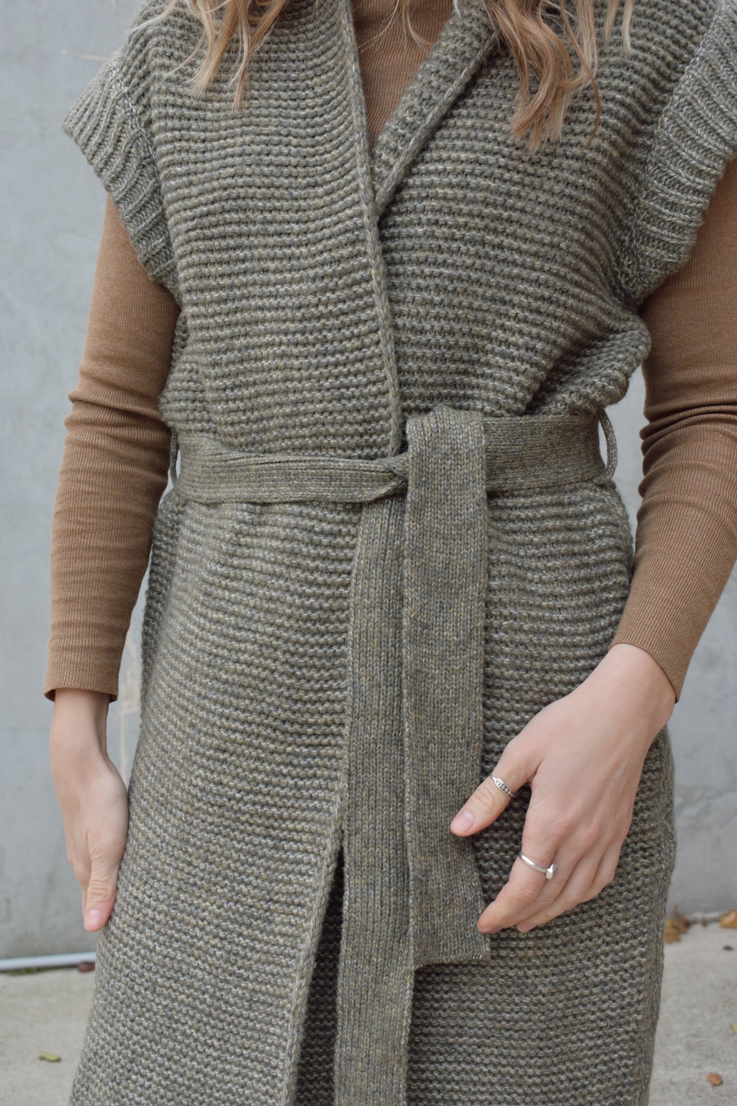 belted sleeveless cardigan vest with thick cap sleeve detail. woven olive green material. hits above the knee.