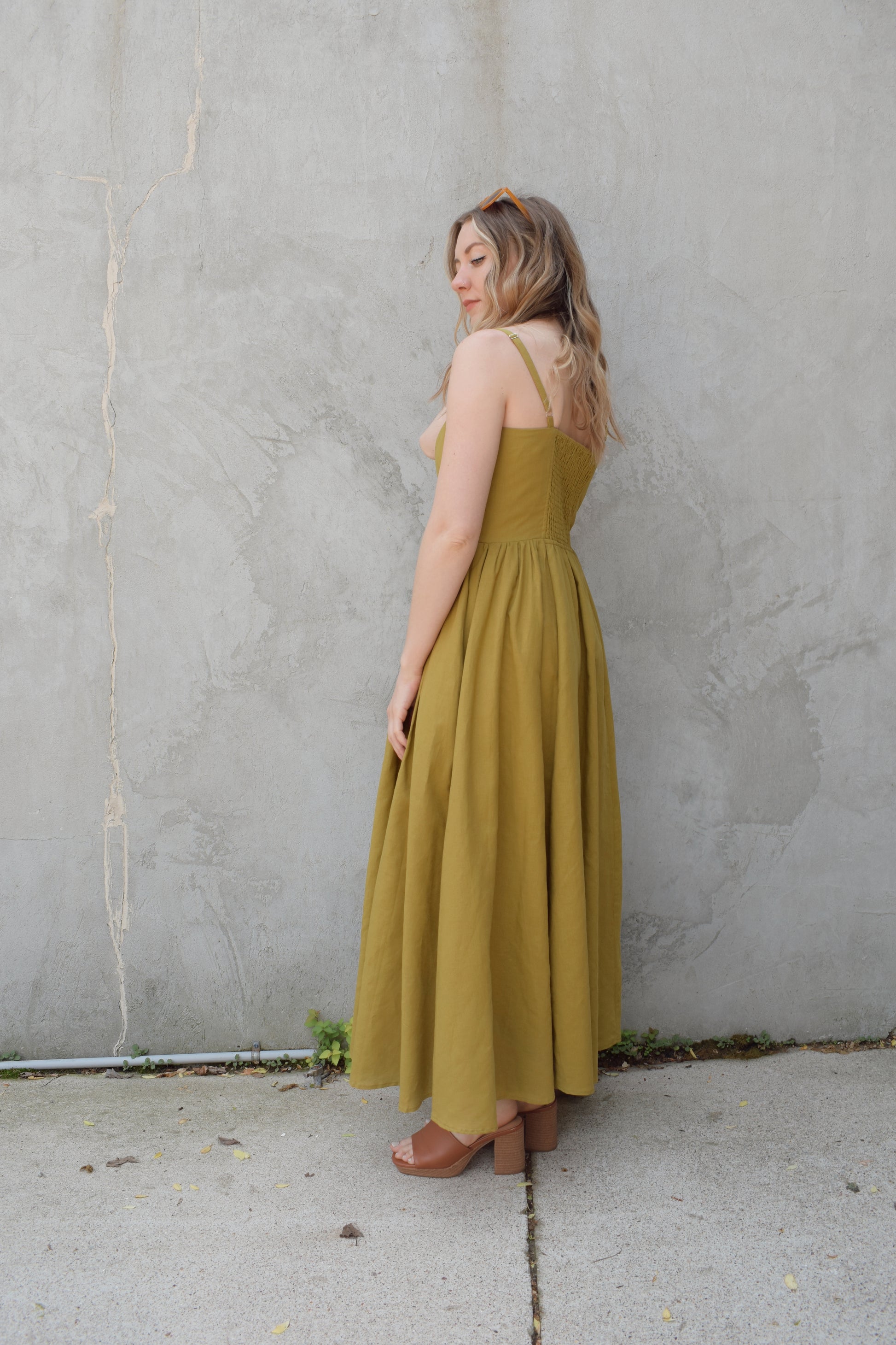 spaghetti strap midi dress with pleats at waistline fitted bodice buttons all down the front that are the same color as the dress, adjustable straps, has pockets, square neckline, smocked panel on back of bodice