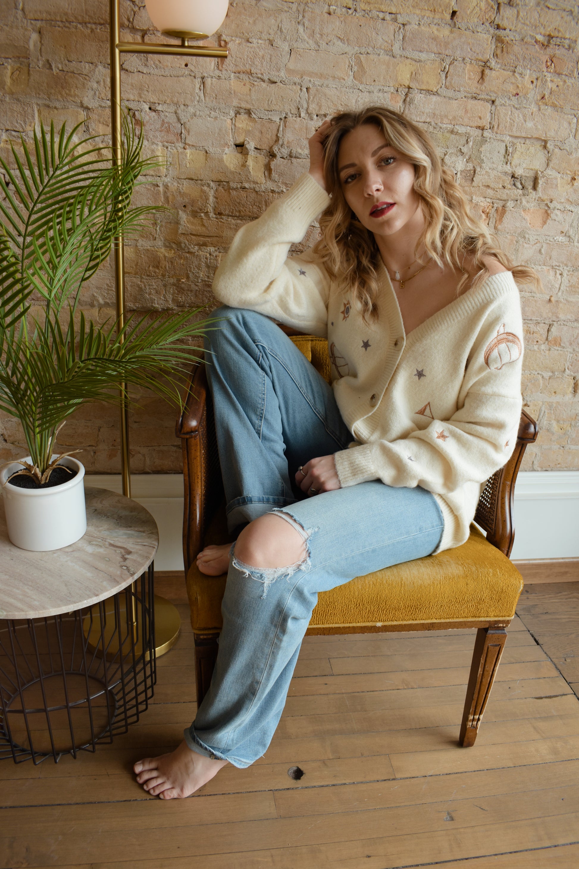 cream slouchy v neck button down cardigan hits just below hips and is embroidered with stars moons and suns has front patch pockets and drop shoulders