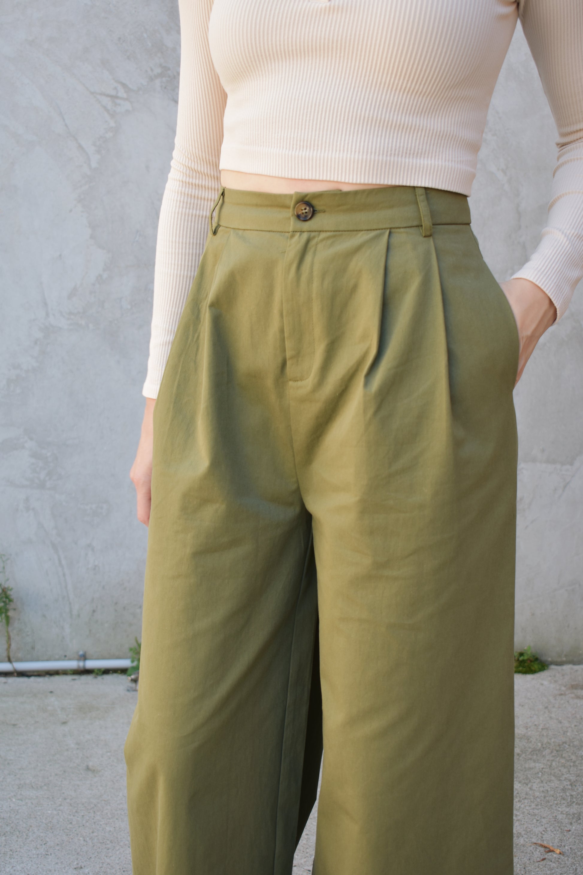 Super wide leg olive green twill trousers with pleats at the top. high waisted with zip and button enclosure. has beltloops and pockets. full length. good for tall ladies.