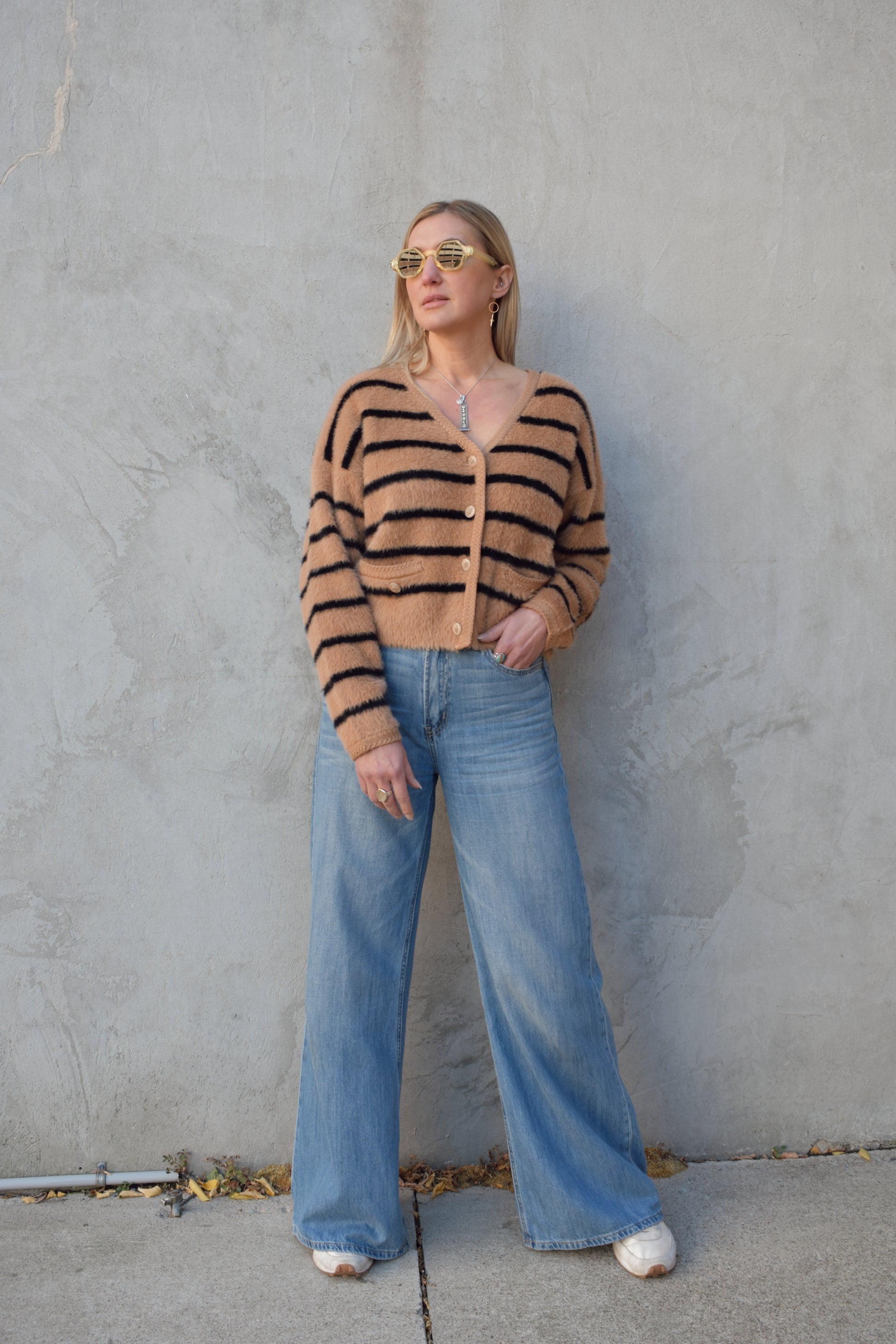 light brown mohair v neck button down cardigan with light brown sailor buttons and black horizontal stripes. two pockets on front that open at the top. outlined with a braided texture on neck line and down the front and on edge of pockets. drop shoulders, slightly cropped.