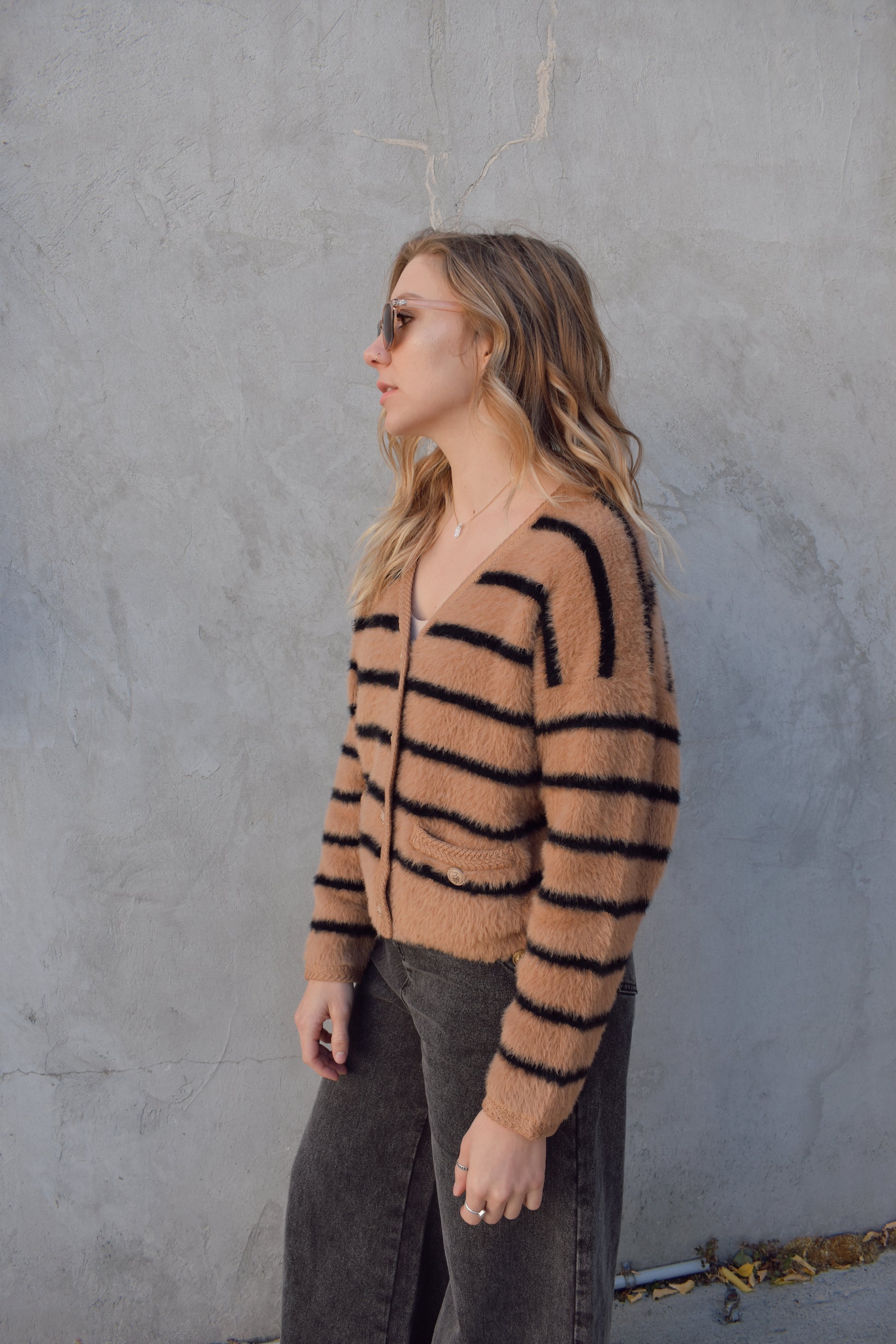 light brown mohair v neck button down cardigan with light brown sailor buttons and black horizontal stripes. two pockets on front that open at the top. outlined with a braided texture on neck line and down the front and on edge of pockets. drop shoulders, slightly cropped.