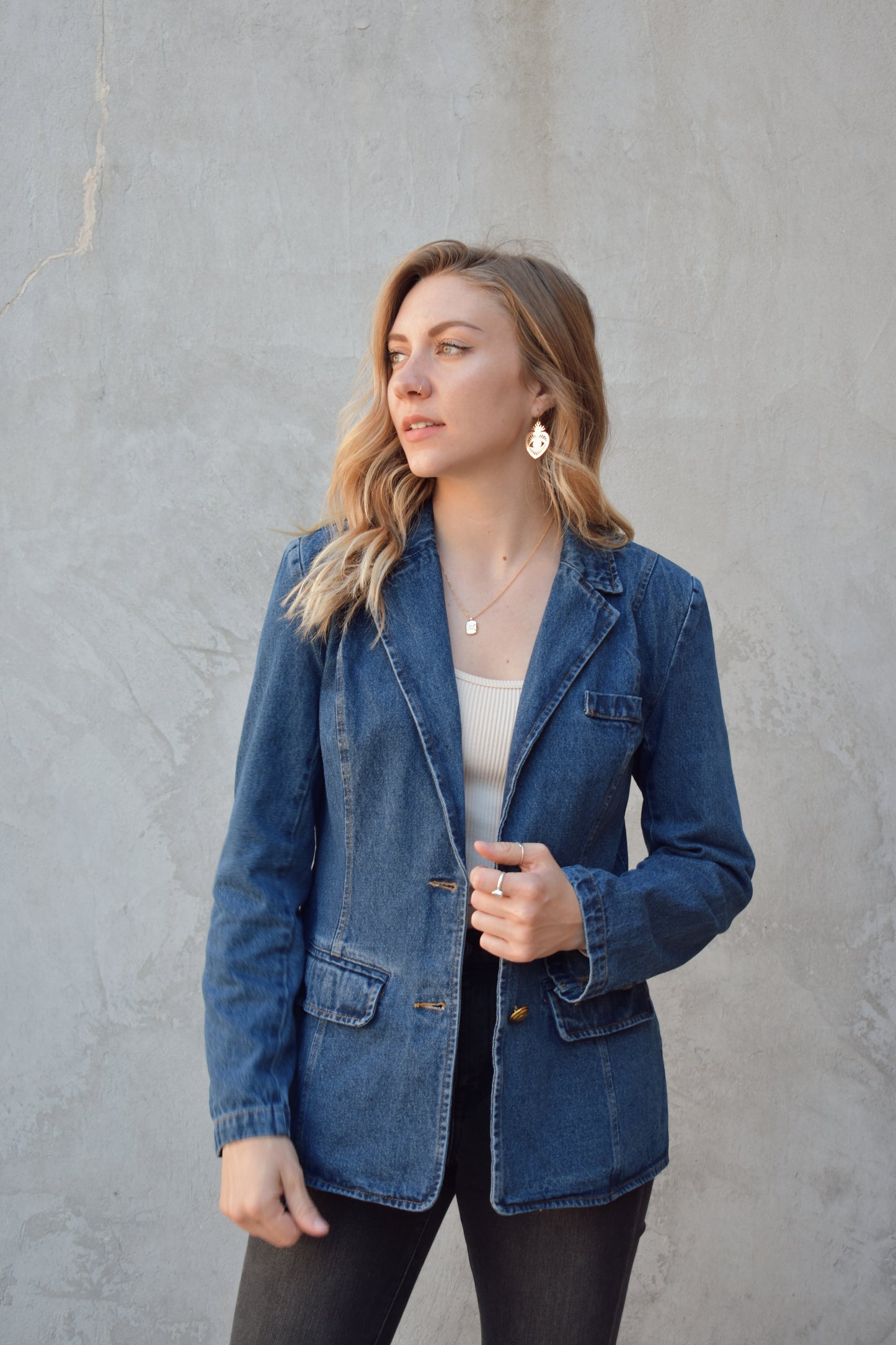 dark wash denim blazer with two gold buttons with an anchor design on them.  pockets with flaps on top, one breast pocket, fitted. full length. slit on back middle hem