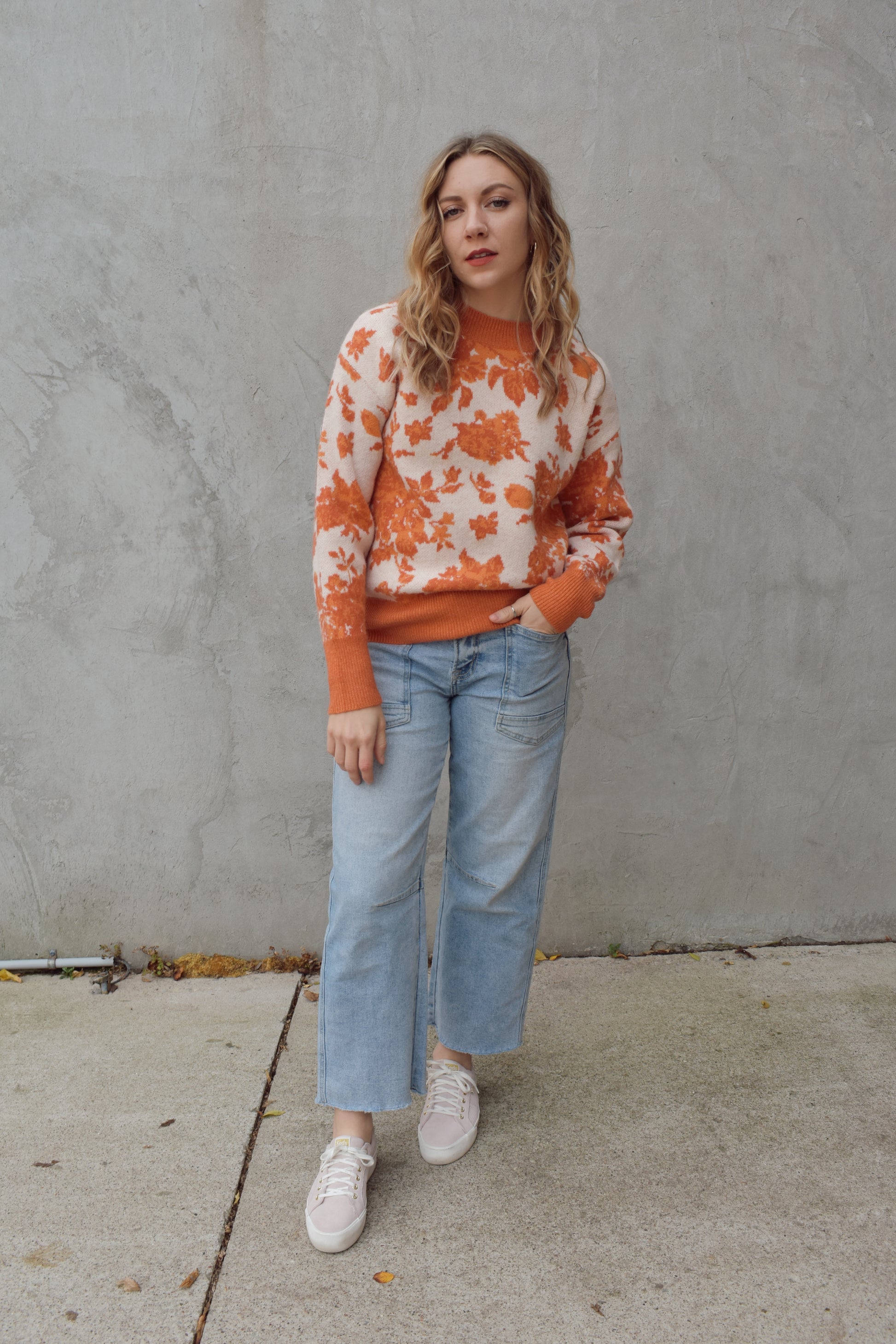 ivory and shades of orange high neck sweater with a leafy floral design. hemline neckline and cuffs are solid orange and ribbed. full length, relaxed fit, drop shoulder.