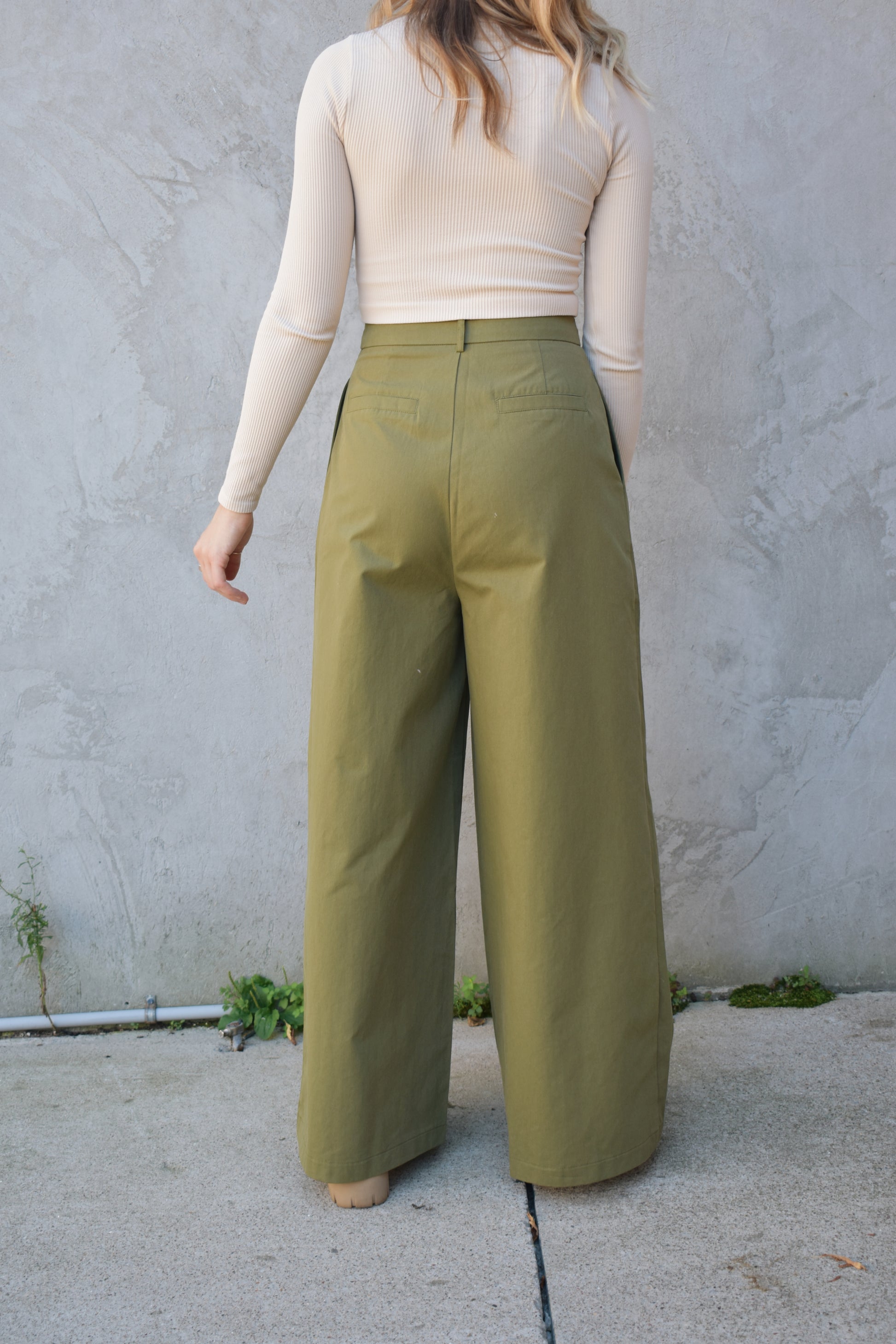 Super wide leg olive green twill trousers with pleats at the top. high waisted with zip and button enclosure. has beltloops and pockets. full length. good for tall ladies. faux butt pockets