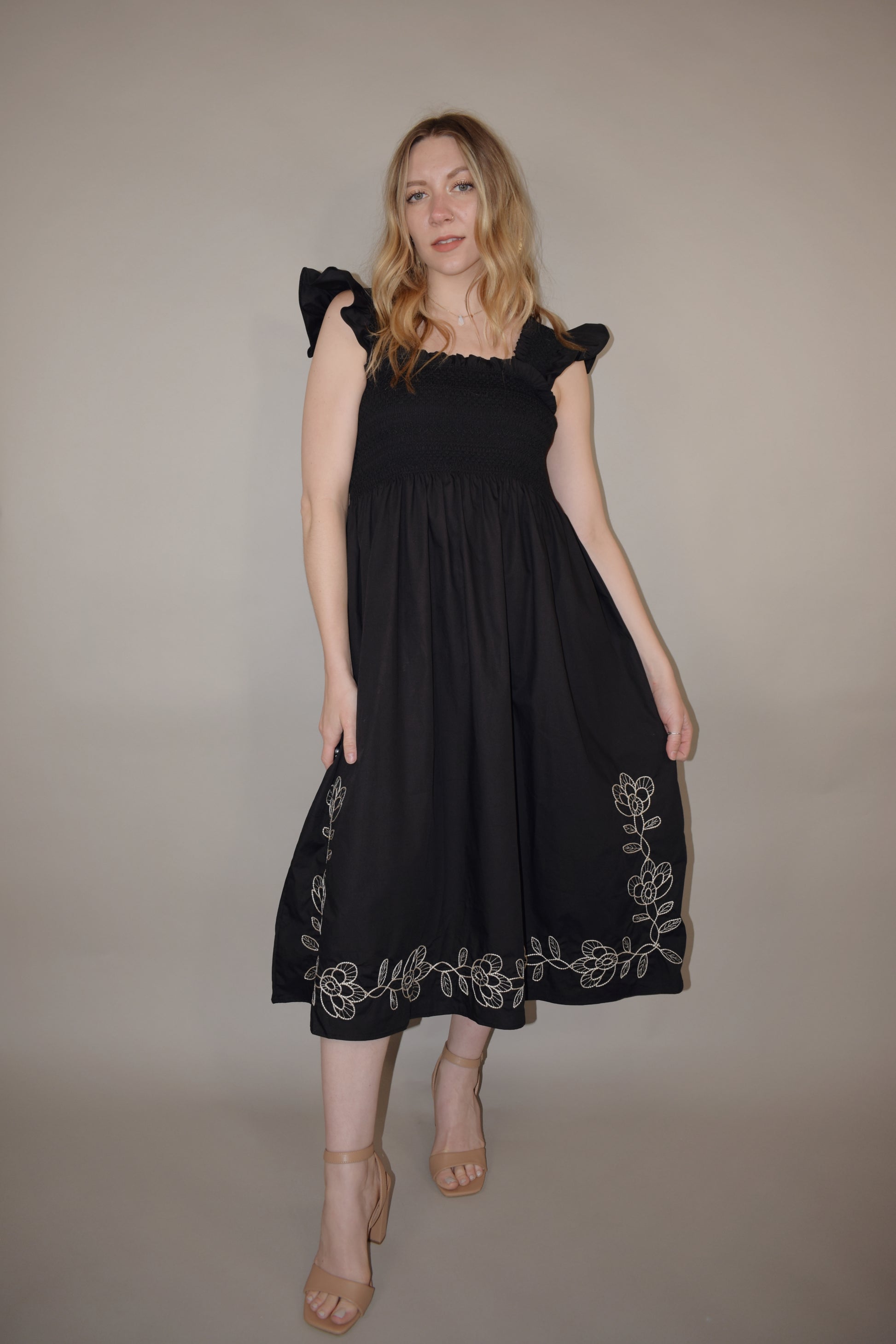 black midi dress with cream embroidered flower vine along hem, smocked bodice, square neckline, flutter shoulder detail, flowy yet tailored feel