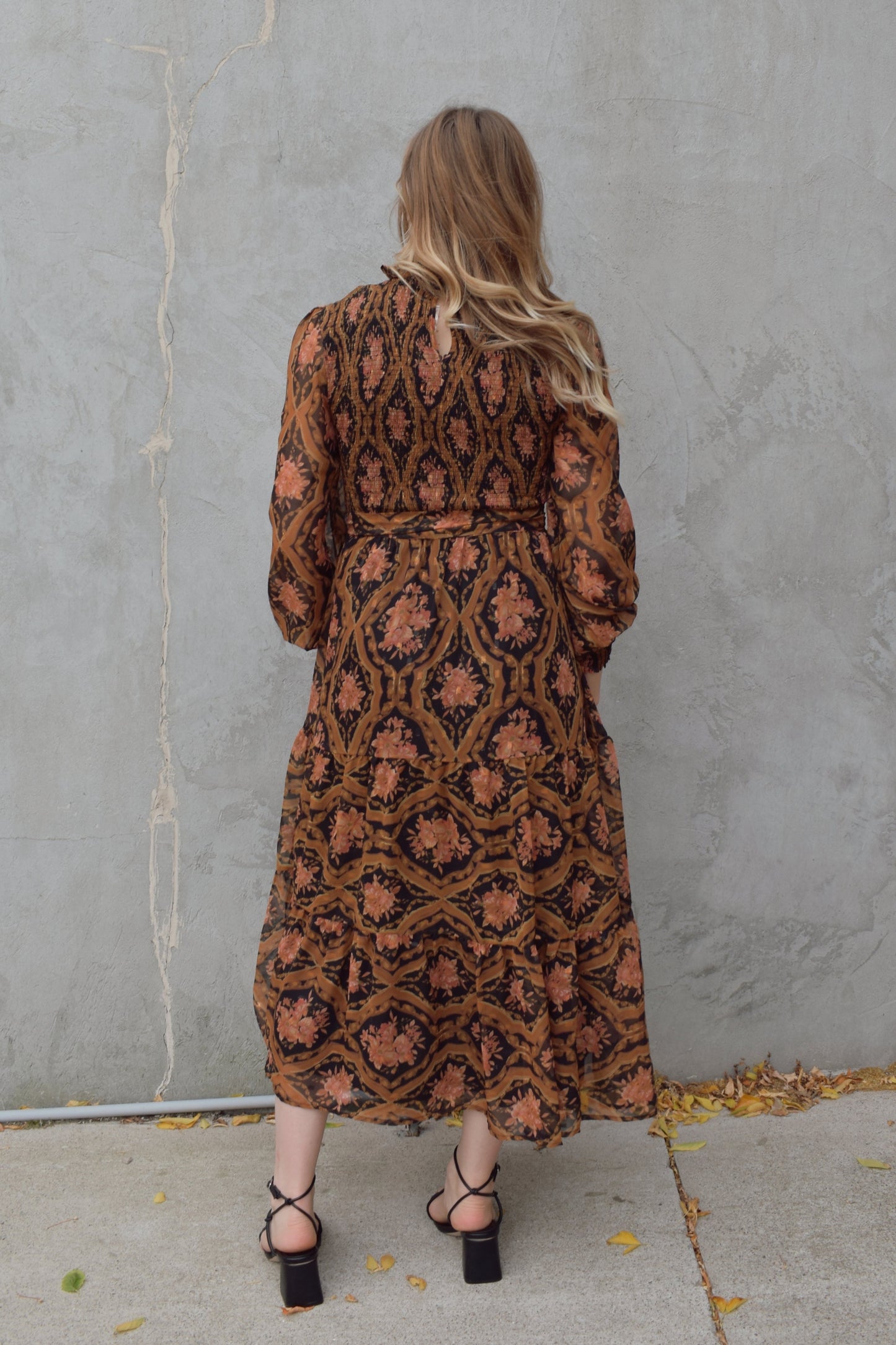 long sleeve high/mock neck midi dress with smocked bodice and cuffs, sheer sleeves, flowy skirt, fabric tie at waist, floral boho tapestry pattern. double button at back of neck