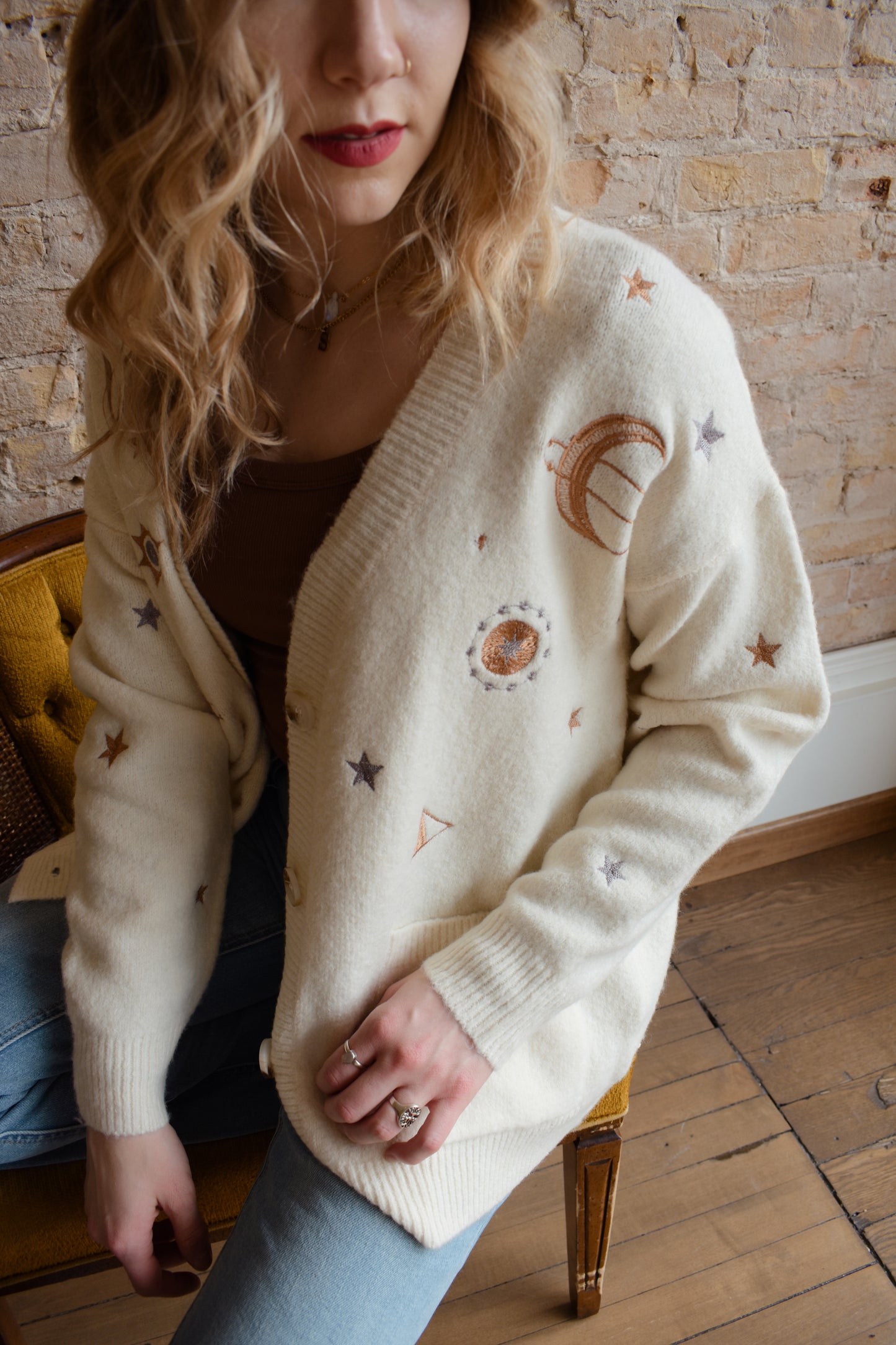 cream slouchy v neck button down cardigan hits just below hips and is embroidered with stars moons and suns has front patch pockets and drop shoulders