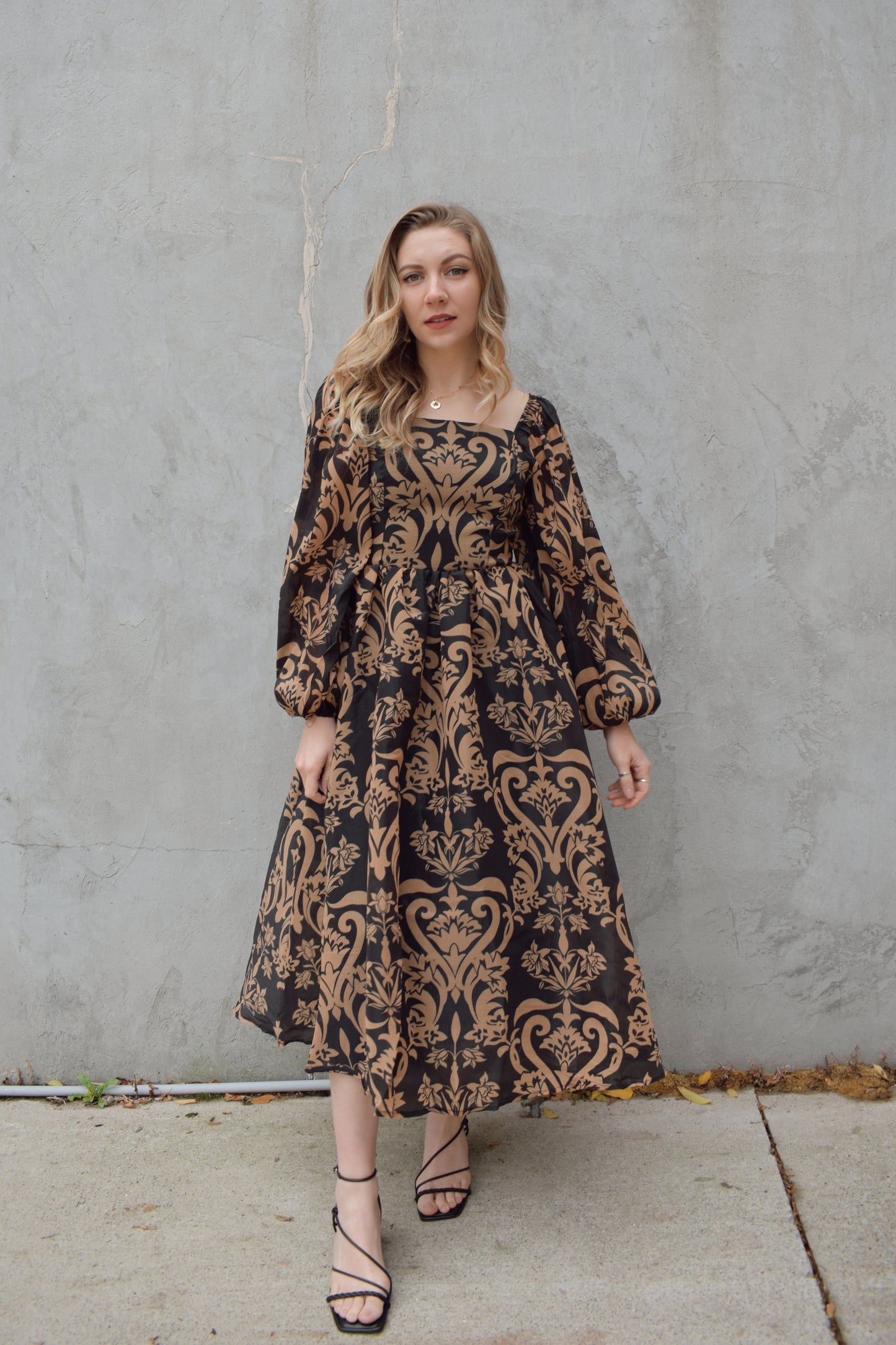 black and dark taupe dark bohemian print midi dress with square neckline front and back, balloon sleeves, flowy skirt, and zip back enclosure