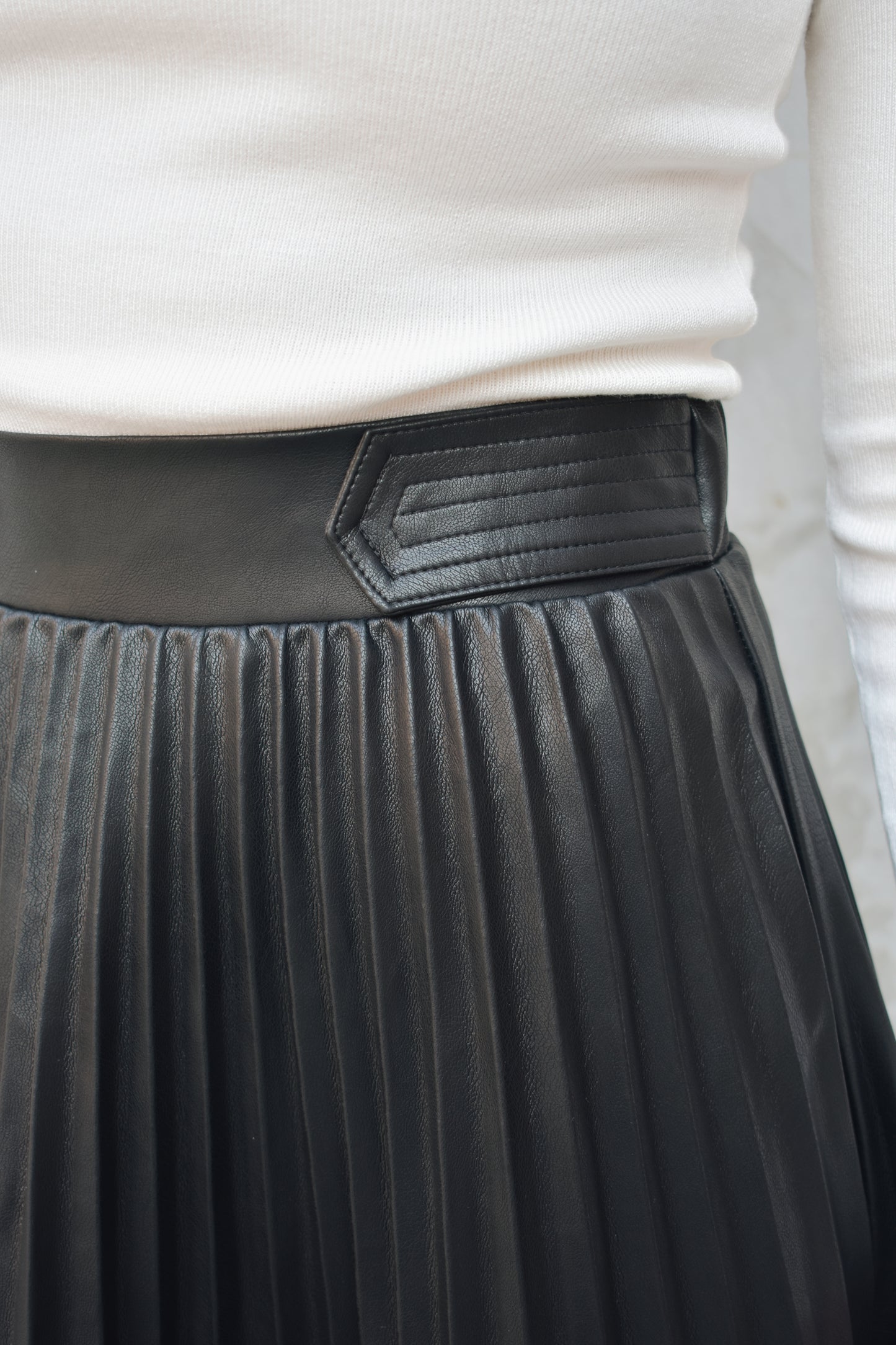 high waisted fully pleated faux leather skirt midi length waist band has tab detailing back of waistband has elastic in band for stretch and it has an invisible zip enclosure on the side