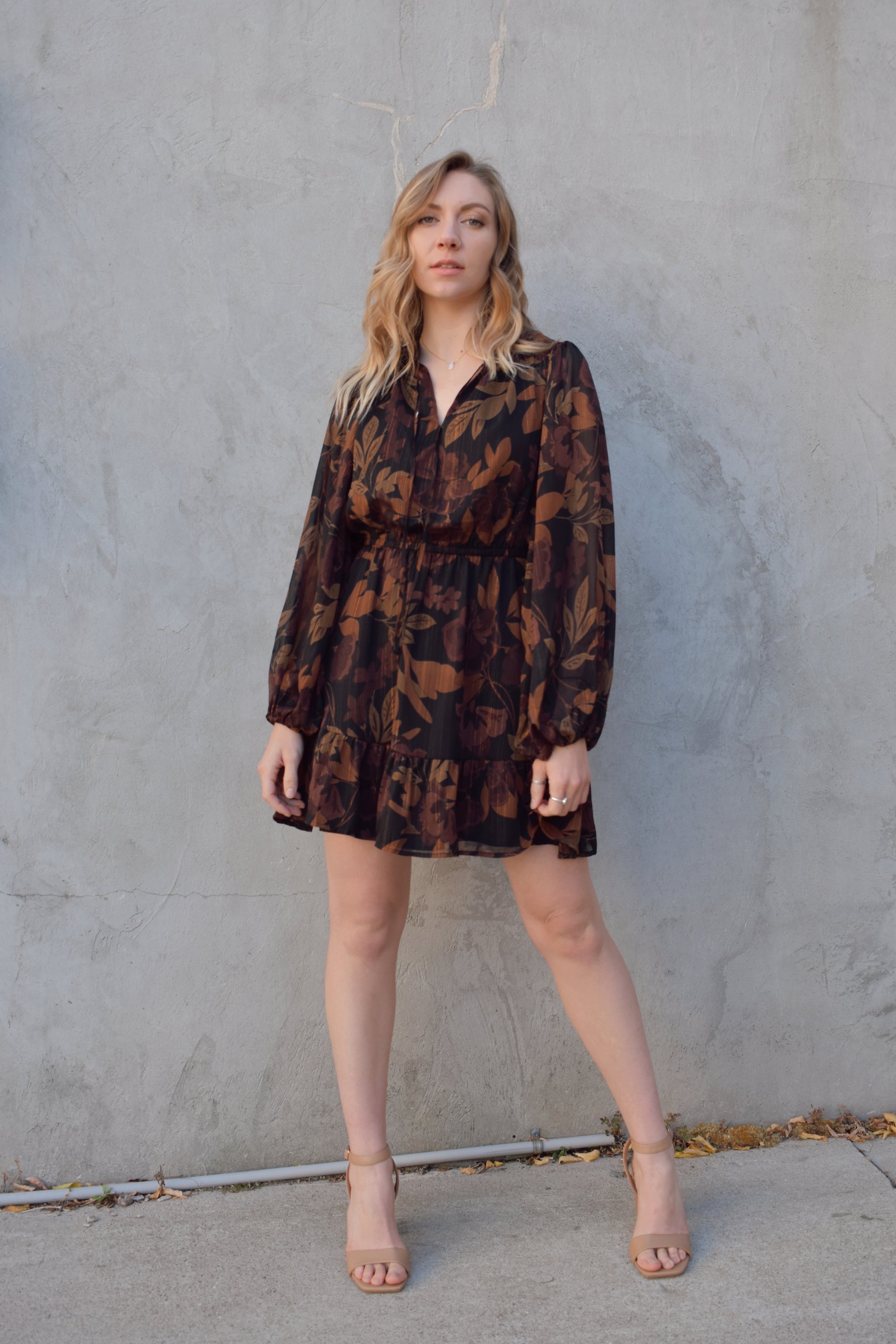 long sleeve chiffon mini dress with leaf print. black background with shades of brown in print. gold tread throughout. sheer balloon sleeves. split v neckline with tie, elastic waist, tiered just above hem making it swing and flowy. lined.