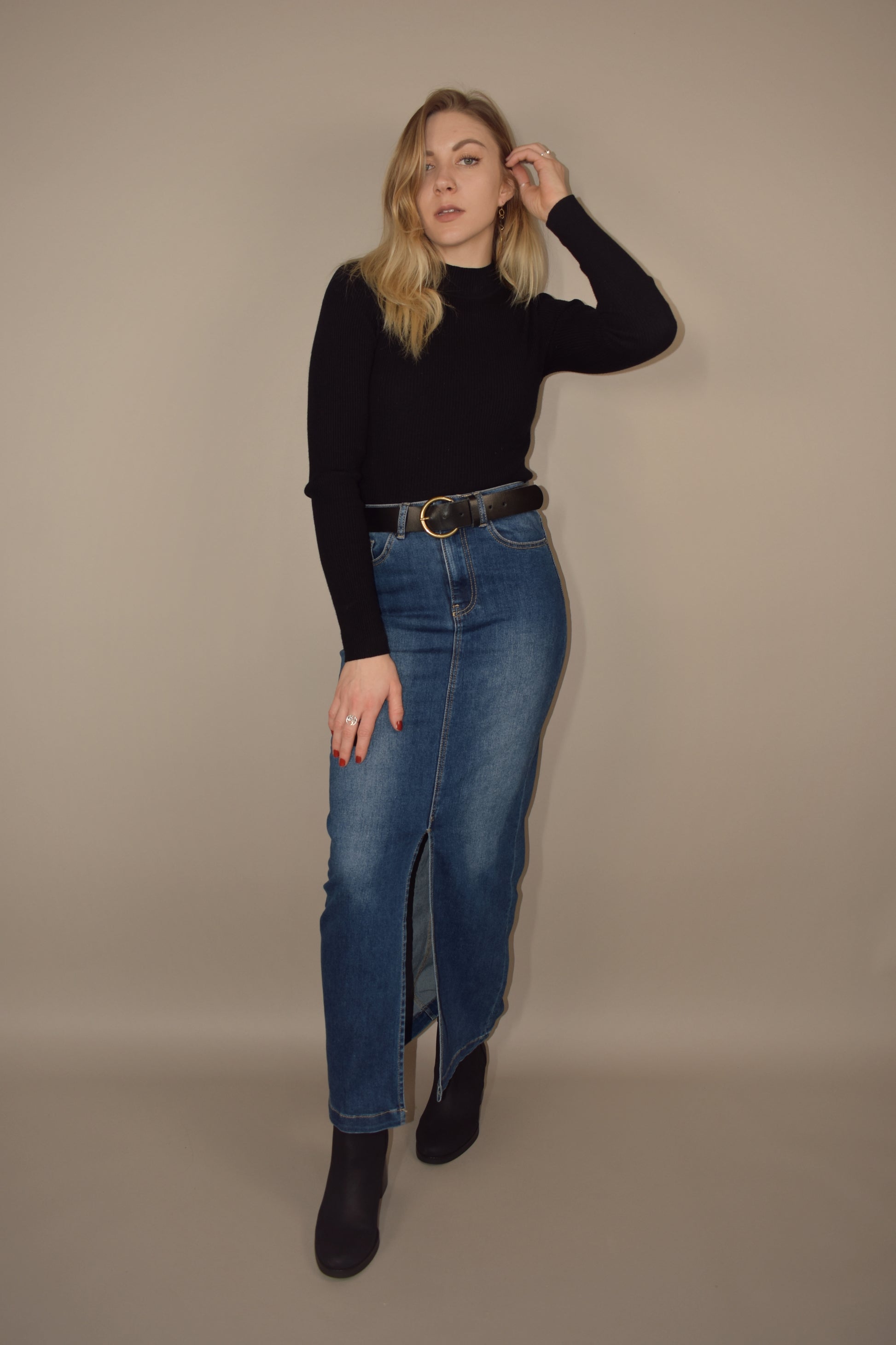 denim midi skirt that is more full length than midi and has a front slit with front and back pockets and is high waisted. made of stretch denim and is a medium dark wash.