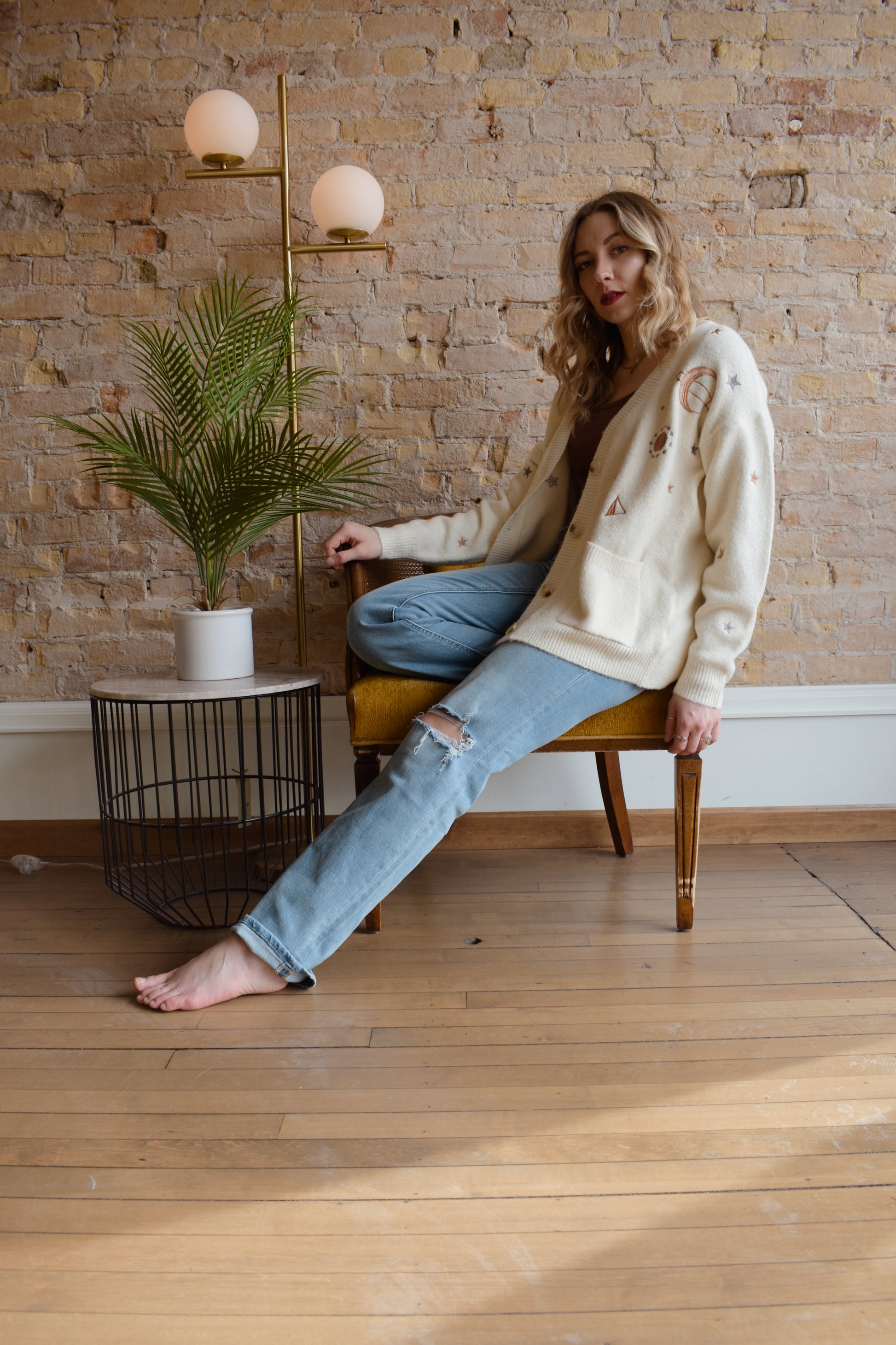 cream slouchy v neck button down cardigan hits just below hips and is embroidered with stars moons and suns has front patch pockets and drop shoulders