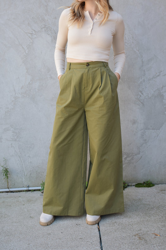 Super wide leg olive green twill trousers with pleats at the top. high waisted with zip and button enclosure. has beltloops and pockets. full length. good for tall ladies.