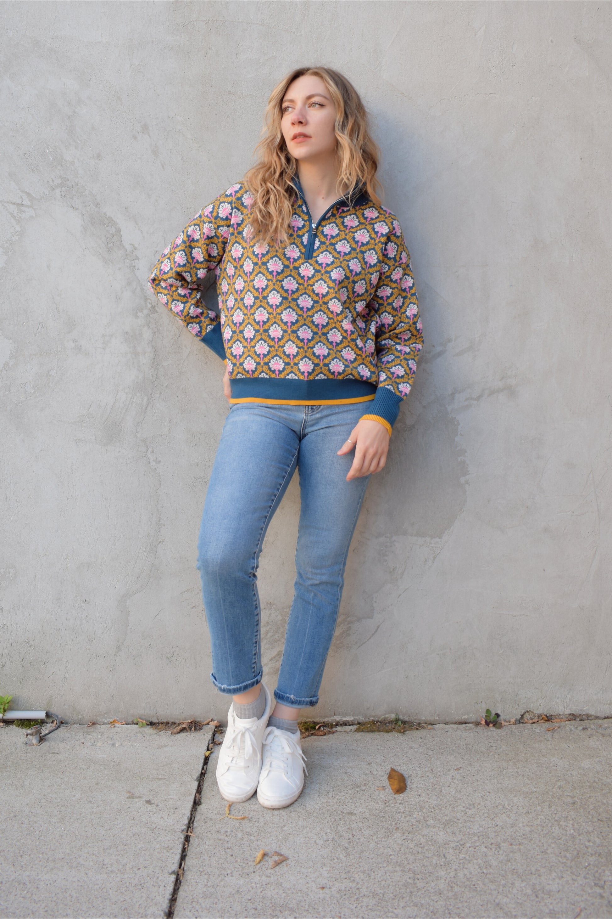 half zip relaxed fit statement pattern pullover with blue and yellow band at ham and cuff and just blue on collar. pattern is yellow, white, and pink on a blue background