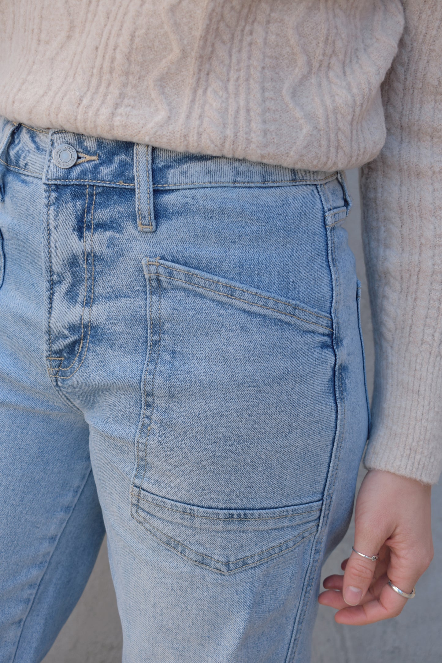 high rise barrel jeans, light wash, stretch denim, no holes, patch pockets in front, back pocket on right has a double pocket detail, zip and button enclosure, has belt loops, raw hem cropped, edgy seam detail at knee