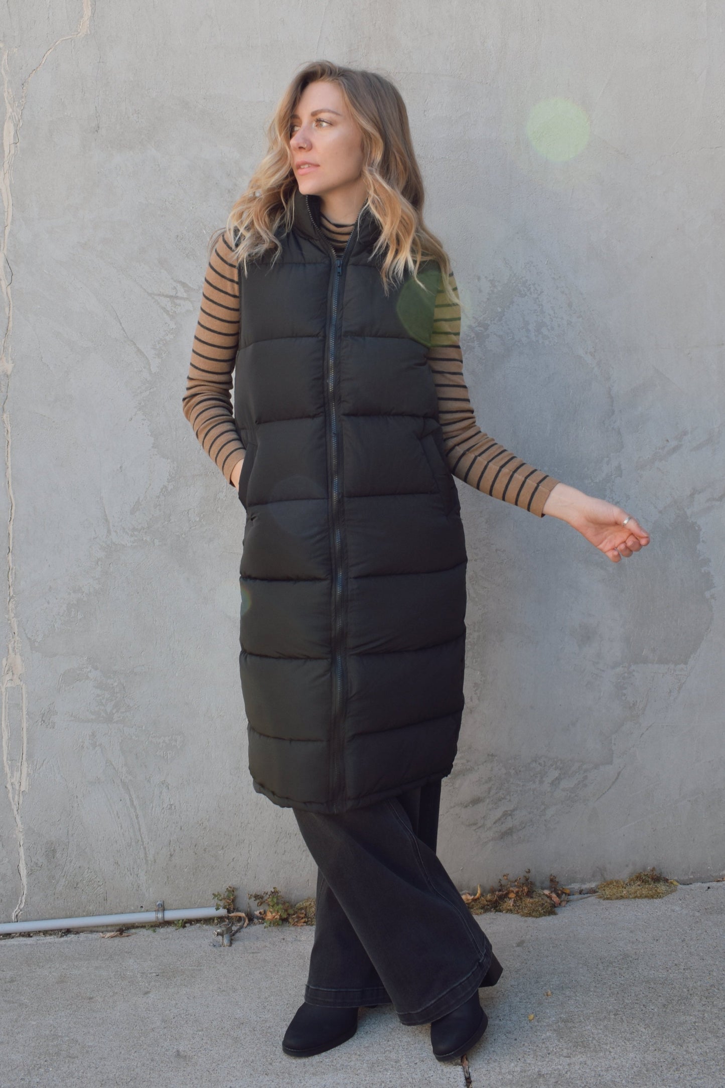 longline black puffer vest. front zip enclosure. has pockets. hits just below the knee.