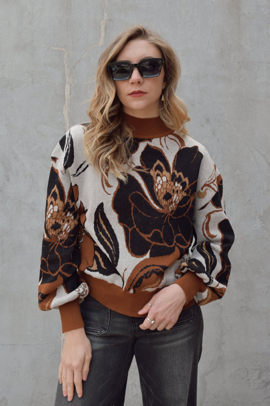 full length relaxed fit mock neck sweater with big floral design in white, black and shades of brown. balloon sleeves with drop shoulder. cuffs, hem and neck line are solid brown and ribbed.