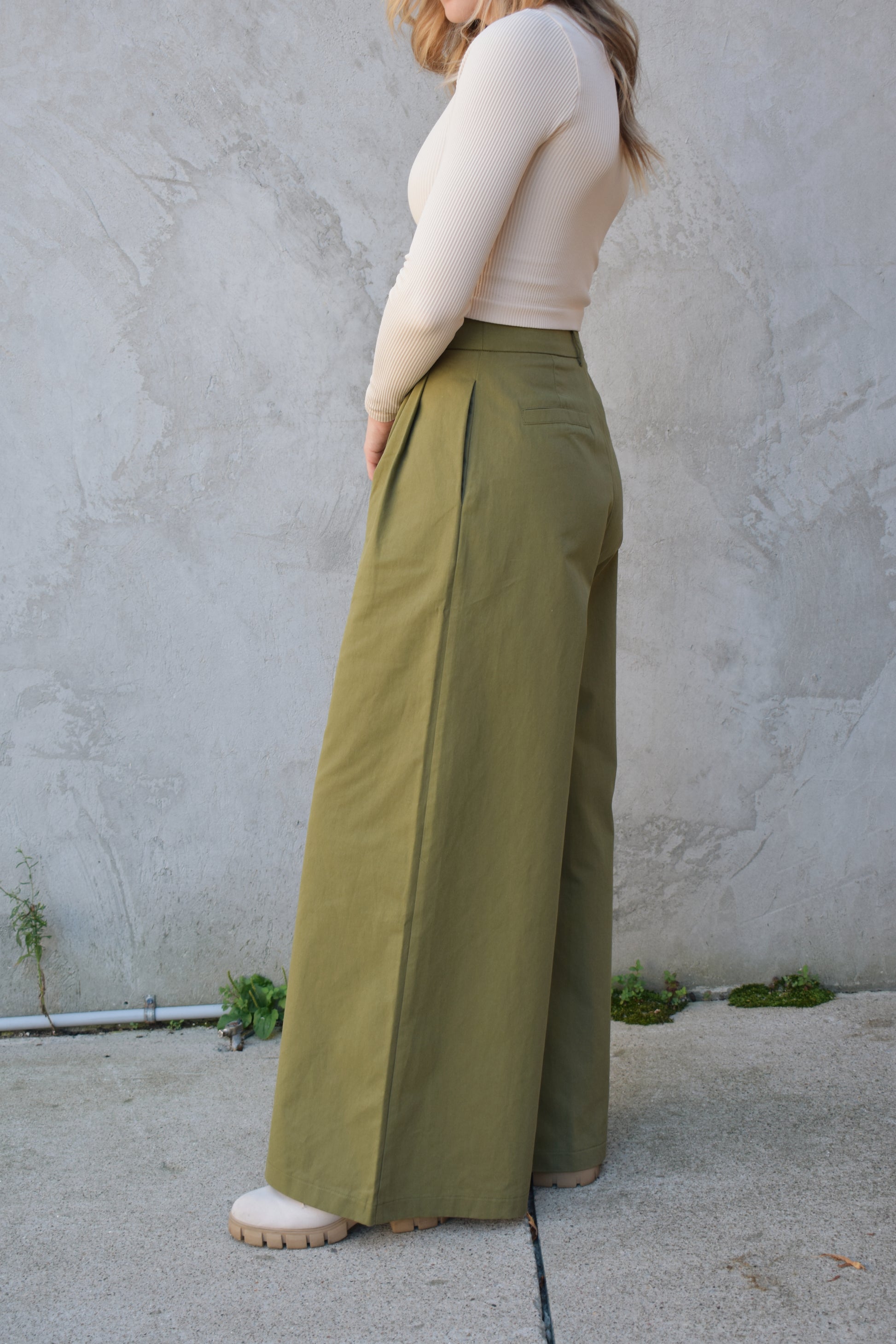 Super wide leg olive green twill trousers with pleats at the top. high waisted with zip and button enclosure. has beltloops and pockets. full length. good for tall ladies.