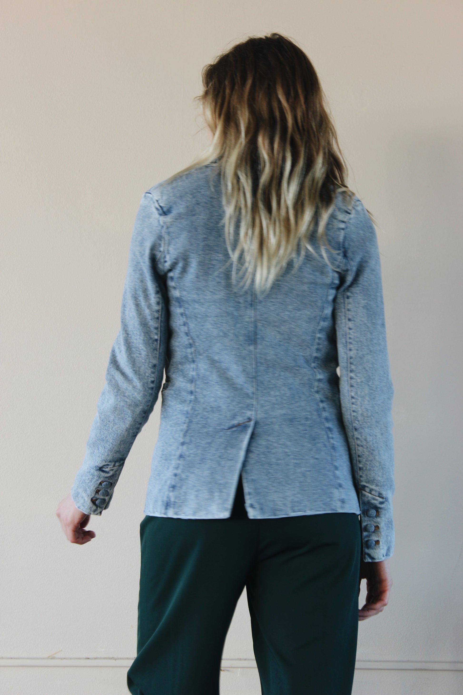 fitted light to medium wash blazer with one denim button enclosure and front pockets that open on the top. slit in back 