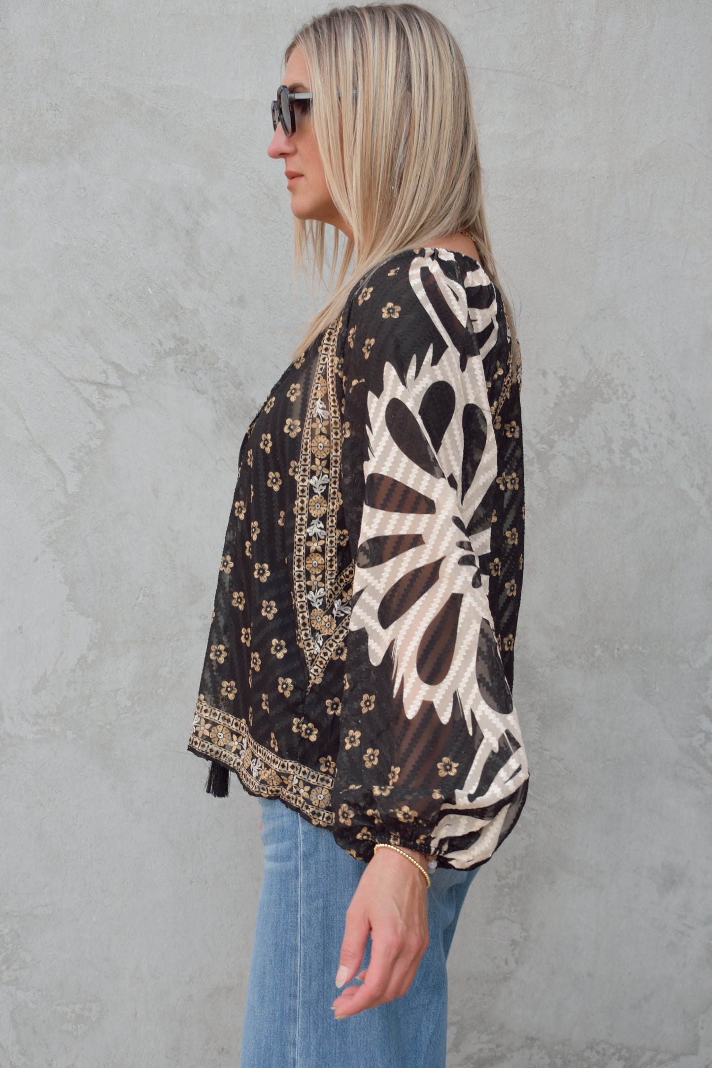 boho sheer long sleeve blouse. black background with gold and cream print. v neck with long tassels. built in black cami liner, not fitted. full length.