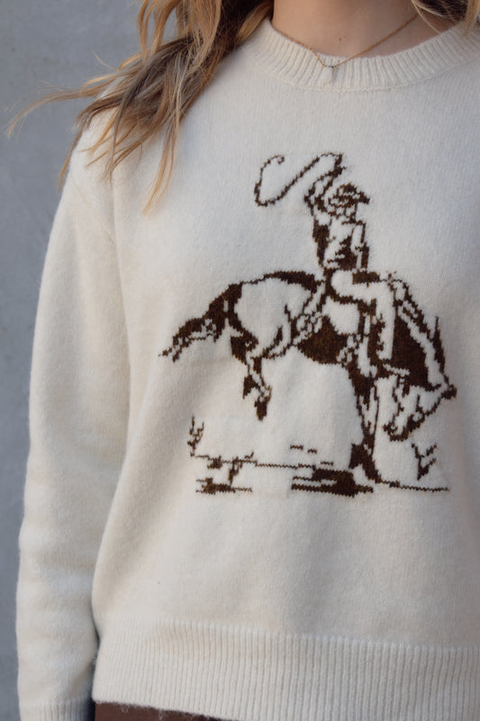 cream colored crew neck sweater relaxed fit full length with cowboy design in brown on front ribbed cuffs hem and neckline drop shoulders