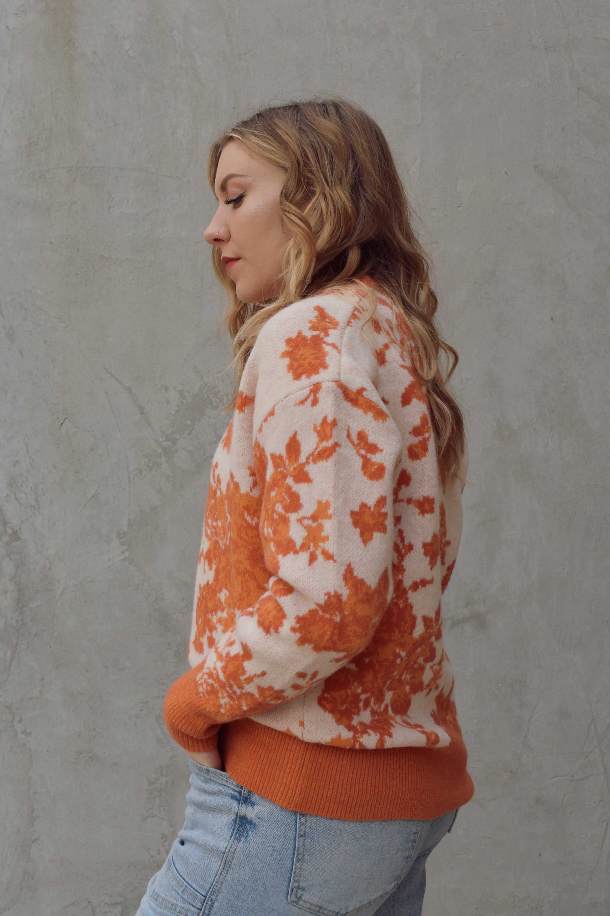 ivory and shades of orange high neck sweater with a leafy floral design. hemline neckline and cuffs are solid orange and ribbed. full length, relaxed fit, drop shoulder.