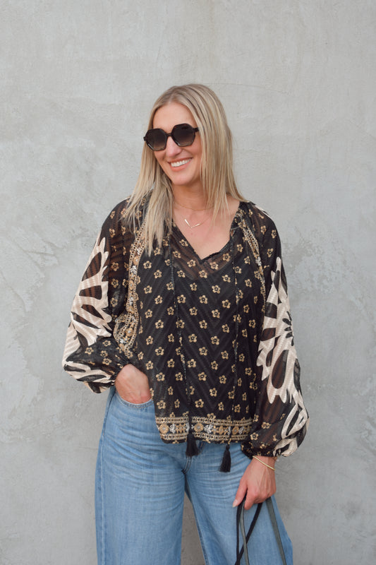 boho sheer long sleeve blouse. black background with gold and cream print. v neck with long tassels. built in black cami liner, not fitted. full length.